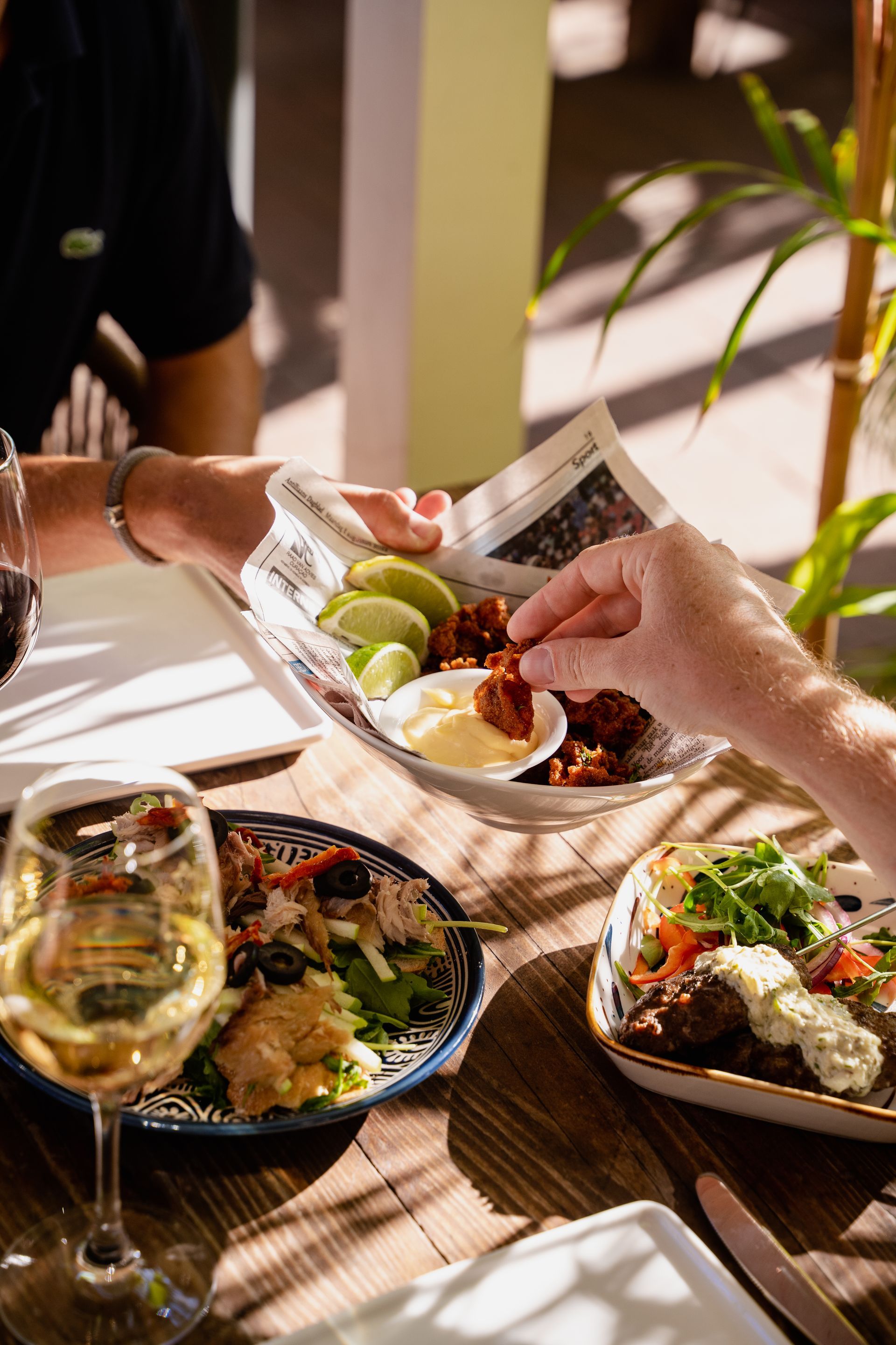 A group of people are sitting at a table eating food and drinking wine.