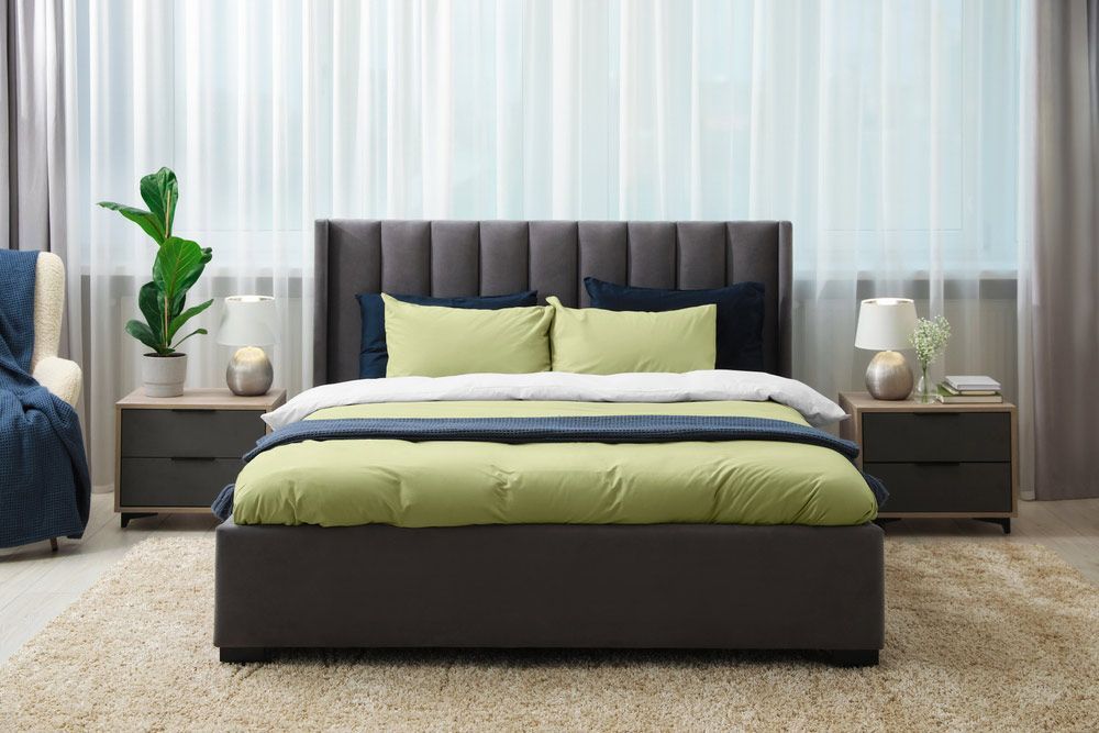 A Bedroom With a Bed, Two Nightstands, a Chair and a Window — Bayside Carpets & Flooring in Kendall, NSW