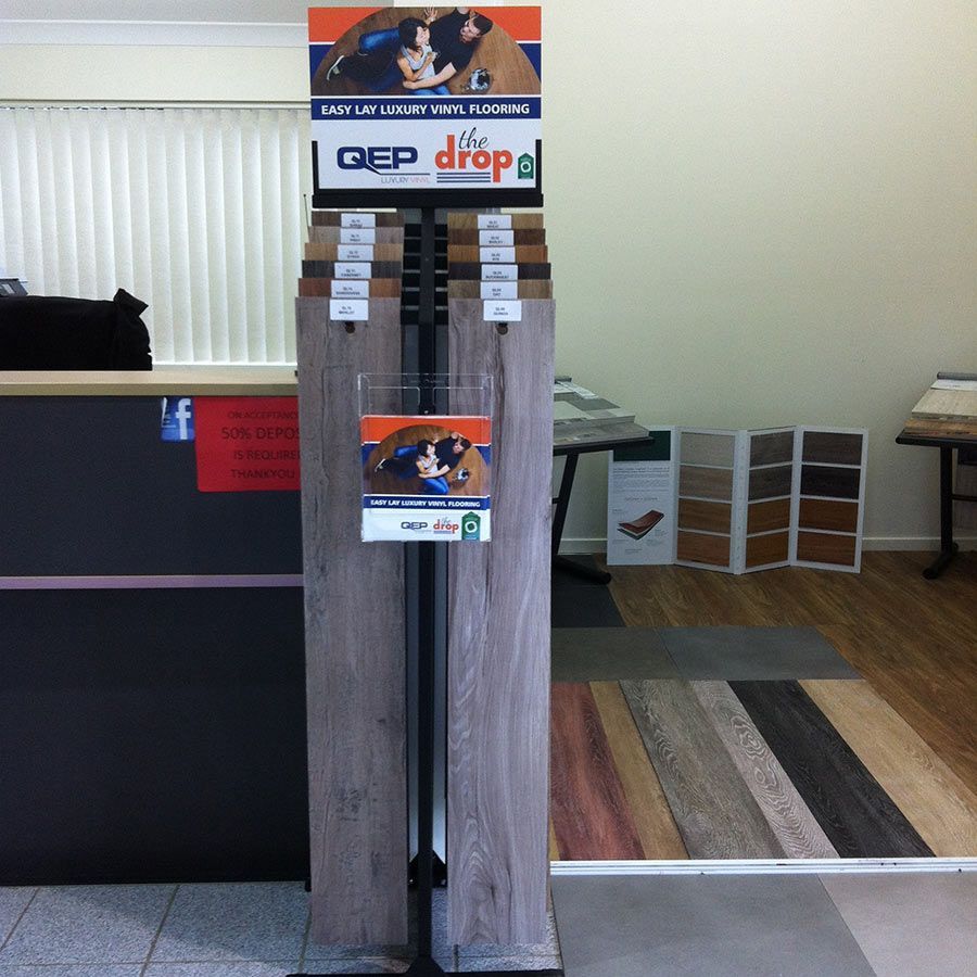 A Wooden Floor Display With a Sign That Says We Drop — Bayside Carpets & Flooring in Wauchope, NSW