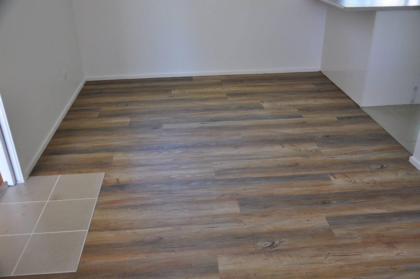 A Room With a Wooden Floor and White Walls — Bayside Carpets & Flooring in Laurieton, NSW