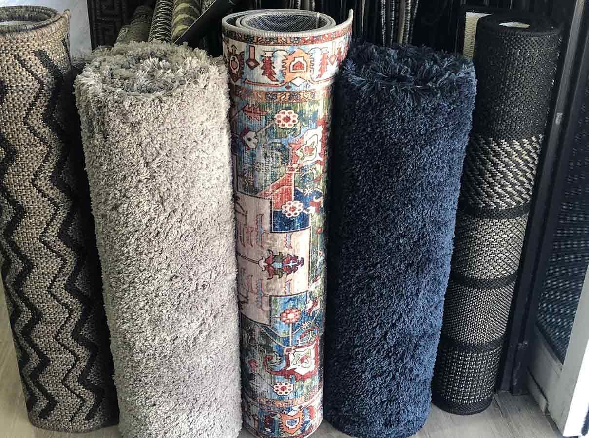 A Bunch of Rugs Are Stacked on Top of Each Other on a Table — Bayside Carpets & Flooring in Laurieton, NSW