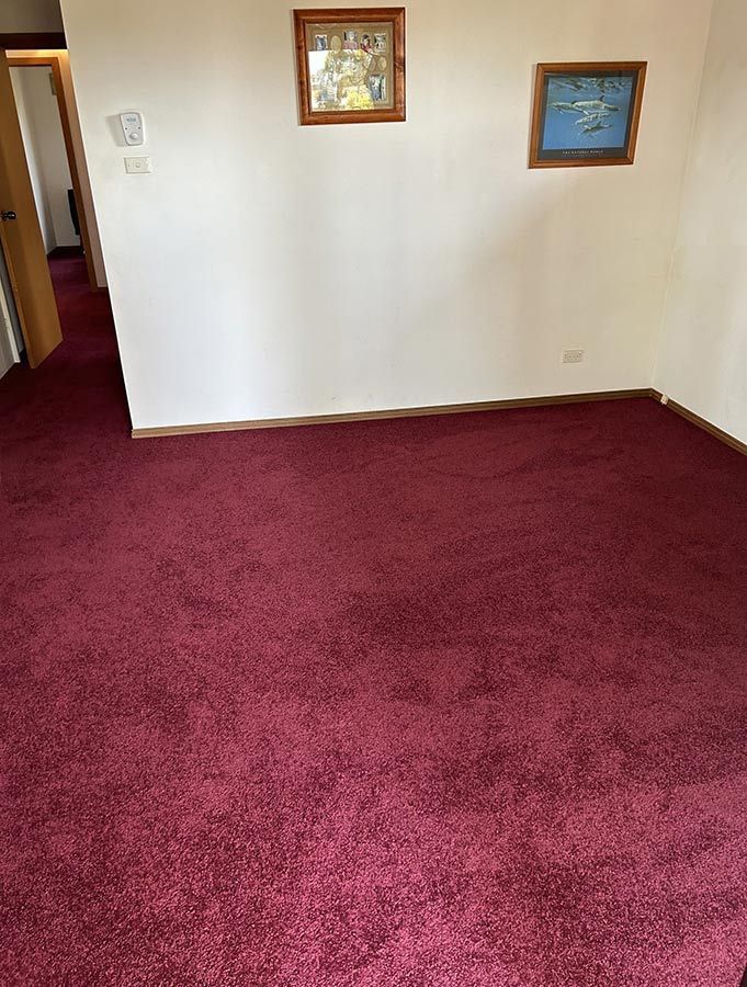 An Empty Room With a Red Carpet and Two Pictures on the Wall — Bayside Carpets & Flooring in Port Macquarie, NSW
