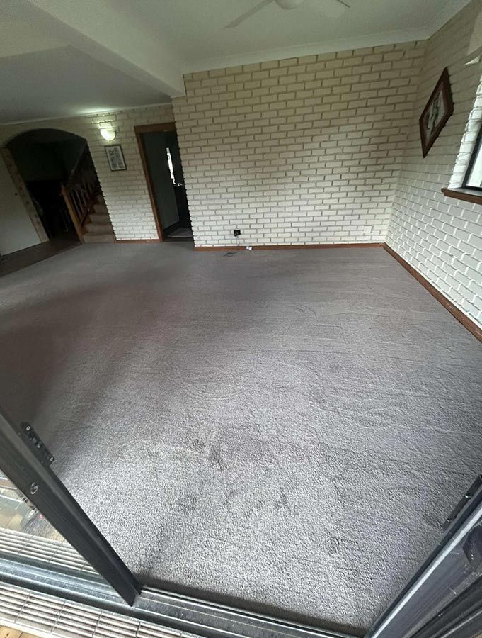An Empty Living Room With a Sliding Glass Door and a Brick Wall — Bayside Carpets & Flooring in Laurieton, NSW