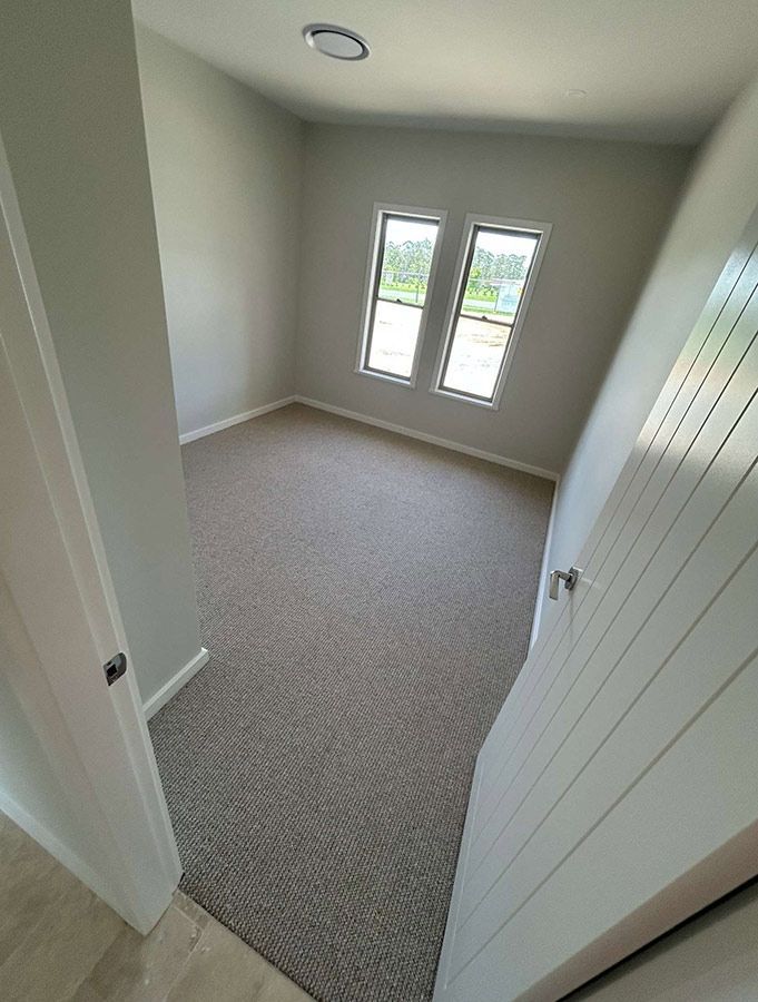 A Bedroom With a Carpeted Floor and Two Windows — Bayside Carpets & Flooring in Laurieton, NSW