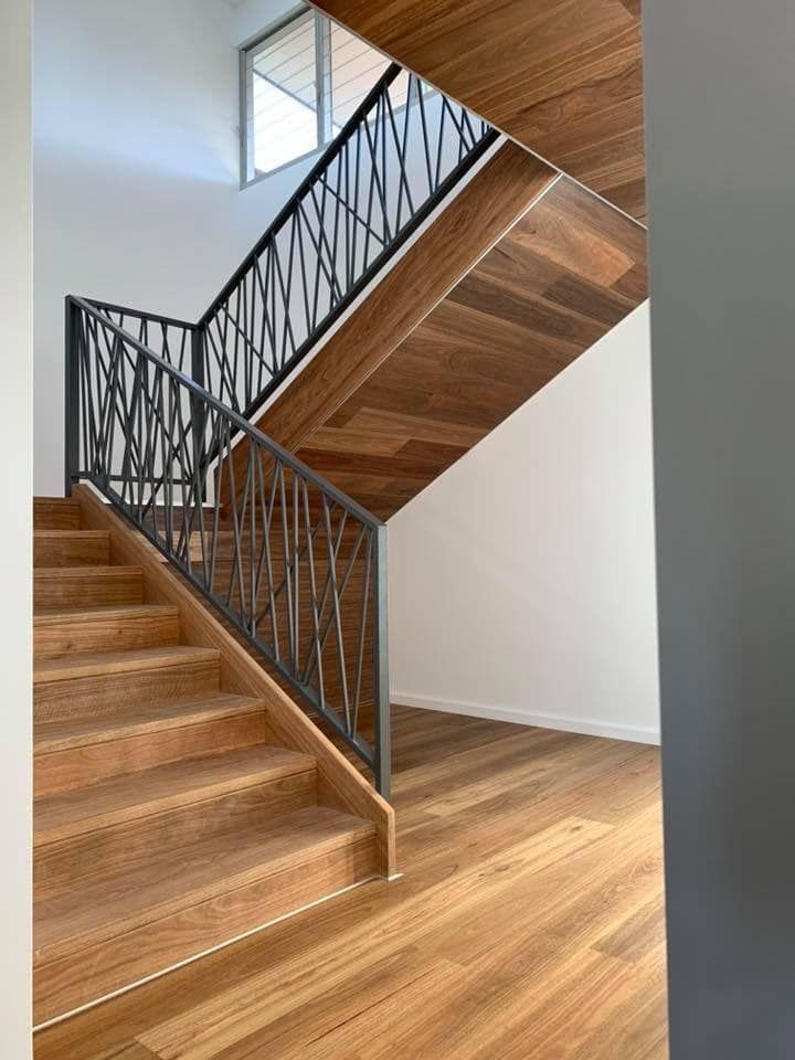 A Wooden Staircase With a Metal Railing in a House — Bayside Carpets & Flooring in Laurieton, NSW
