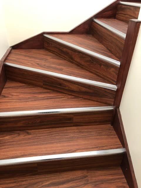 A Close Up of a Wooden Staircase With Metal Trim — Bayside Carpets & Flooring in Laurieton, NSW