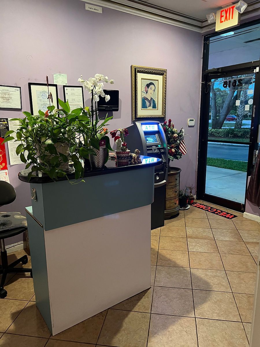 A reception desk in a room with a purple wall and a red exit sign.