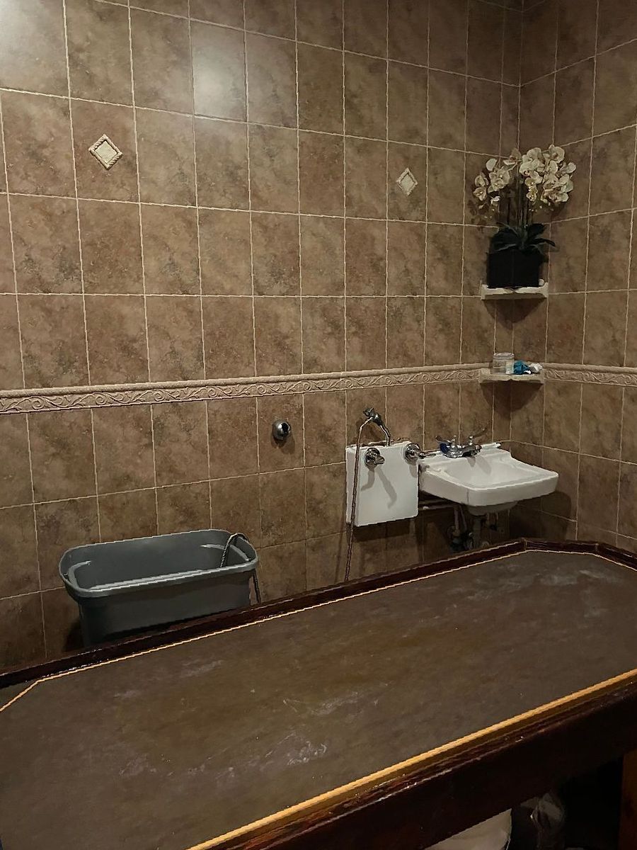 A bathroom with a table , sink , and flowers on the wall.