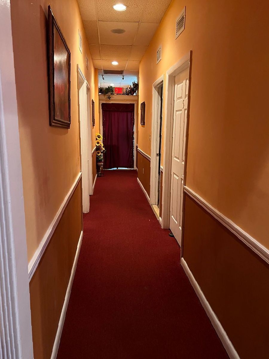 A long hallway with a red carpet and a painting on the wall.