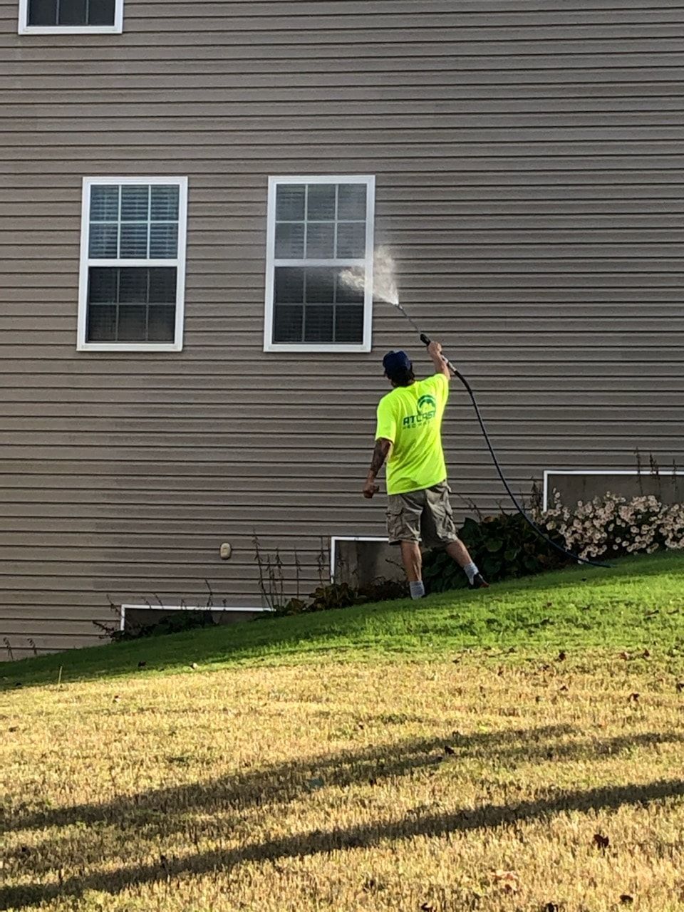 A man is cleaning the side of a house with a hose .