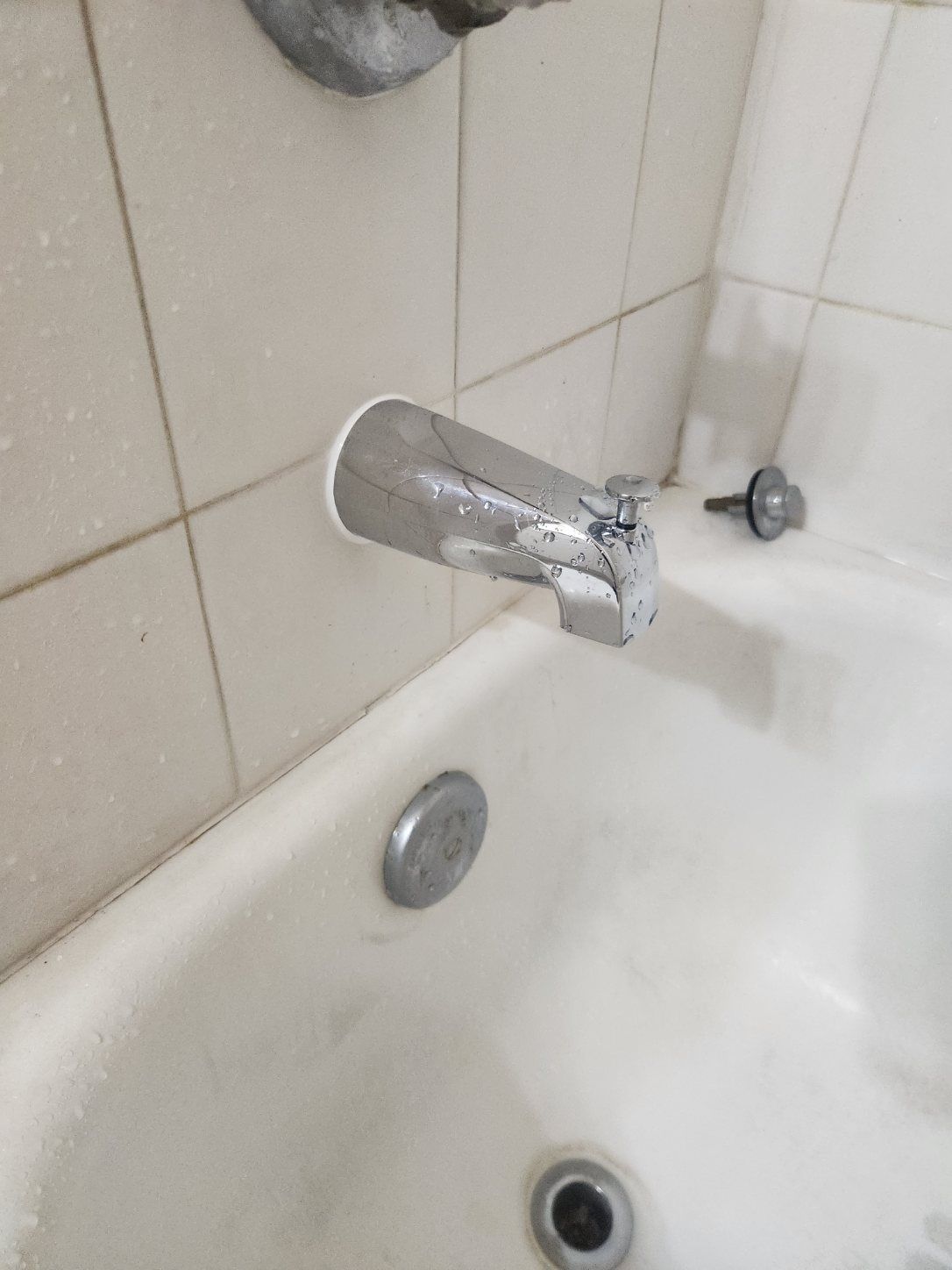 Bathtub with faucet and drain. White tile walls, chrome fixtures.