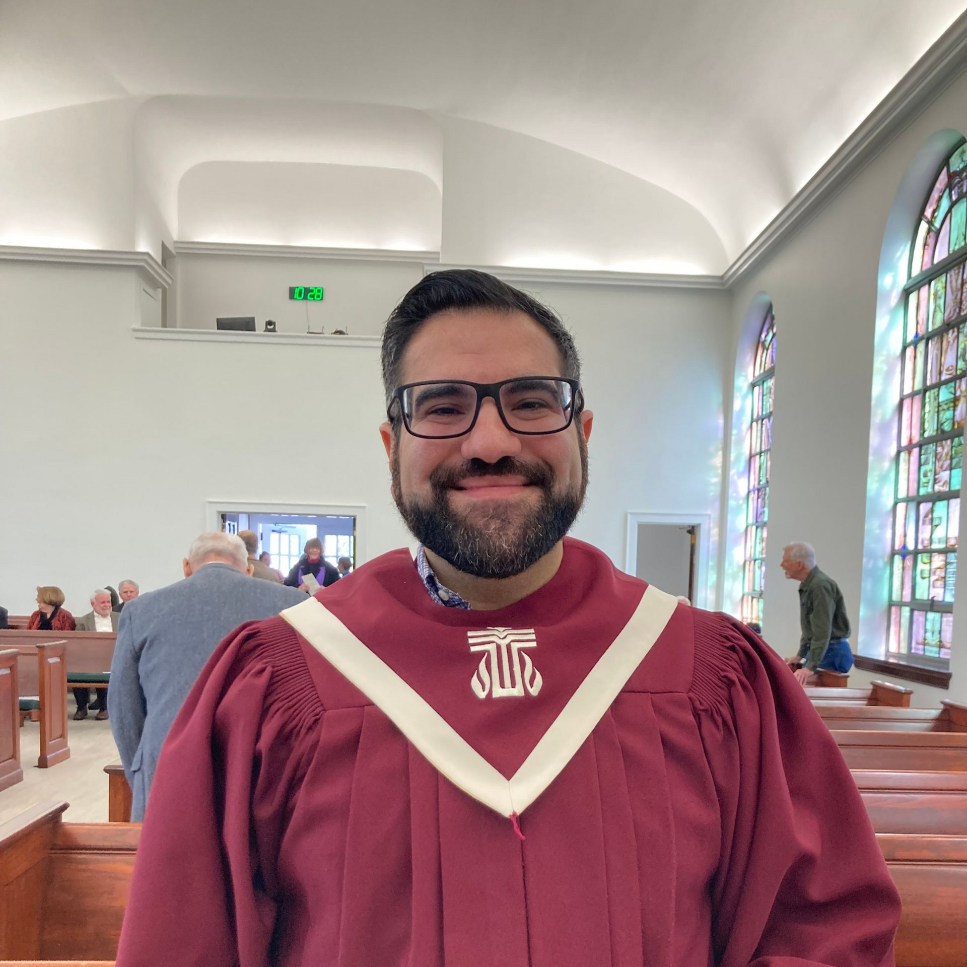 A bald man wearing glasses and a black jacket