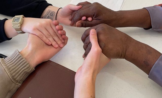 A group of people are holding hands on a table