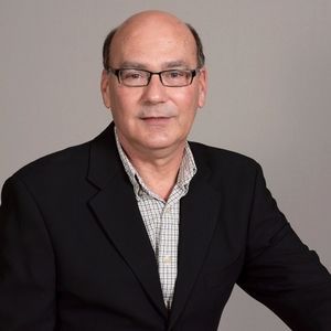 A bald man wearing glasses and a black jacket