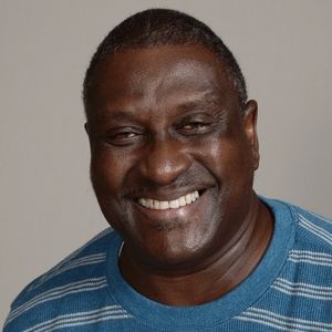 A man wearing a blue striped shirt is smiling for the camera.