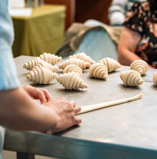 Mani che dispongono forme di argilla o pasta beige su un tavolo di metallo in un ambiente di laboratorio.