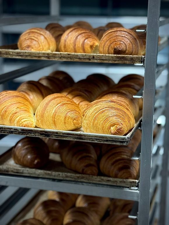 Mani che reggono una fetta di pane giallo con uvetta, che mostra una mollica morbida e ariosa.
