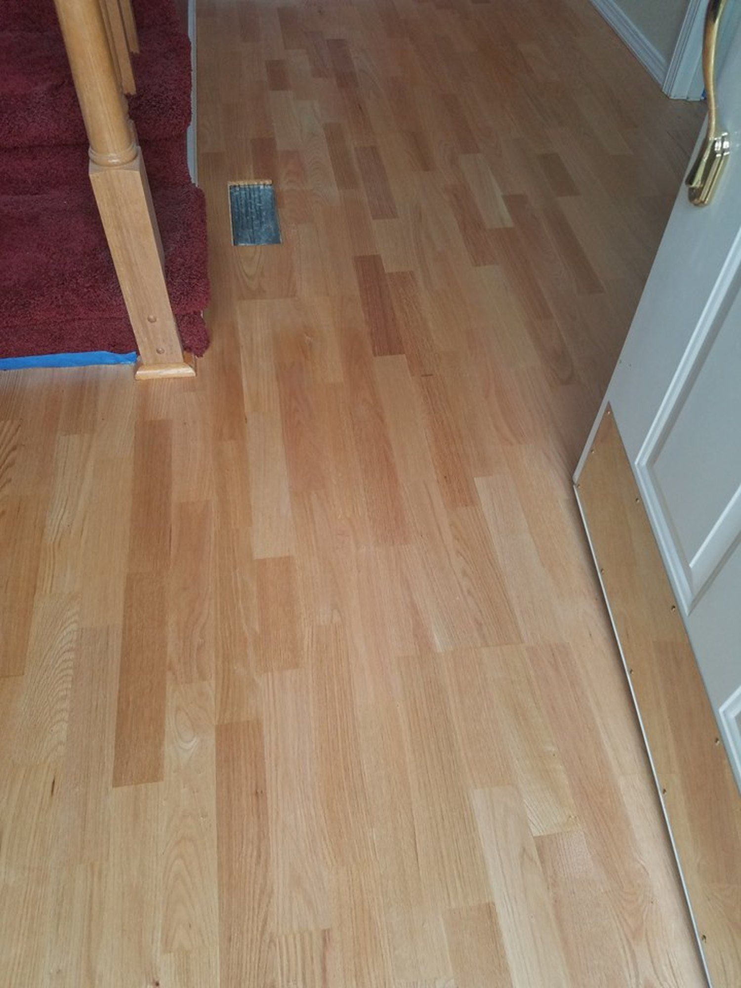 A wooden floor in a room with stairs and a door.