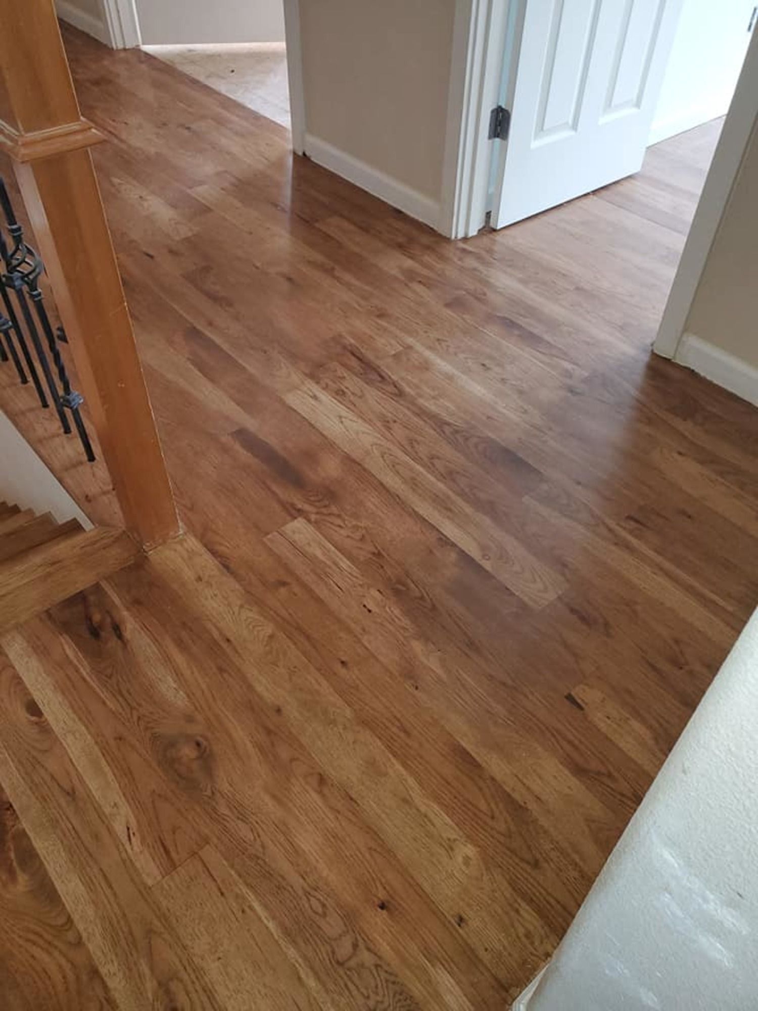 A wooden floor in a hallway next to a staircase.