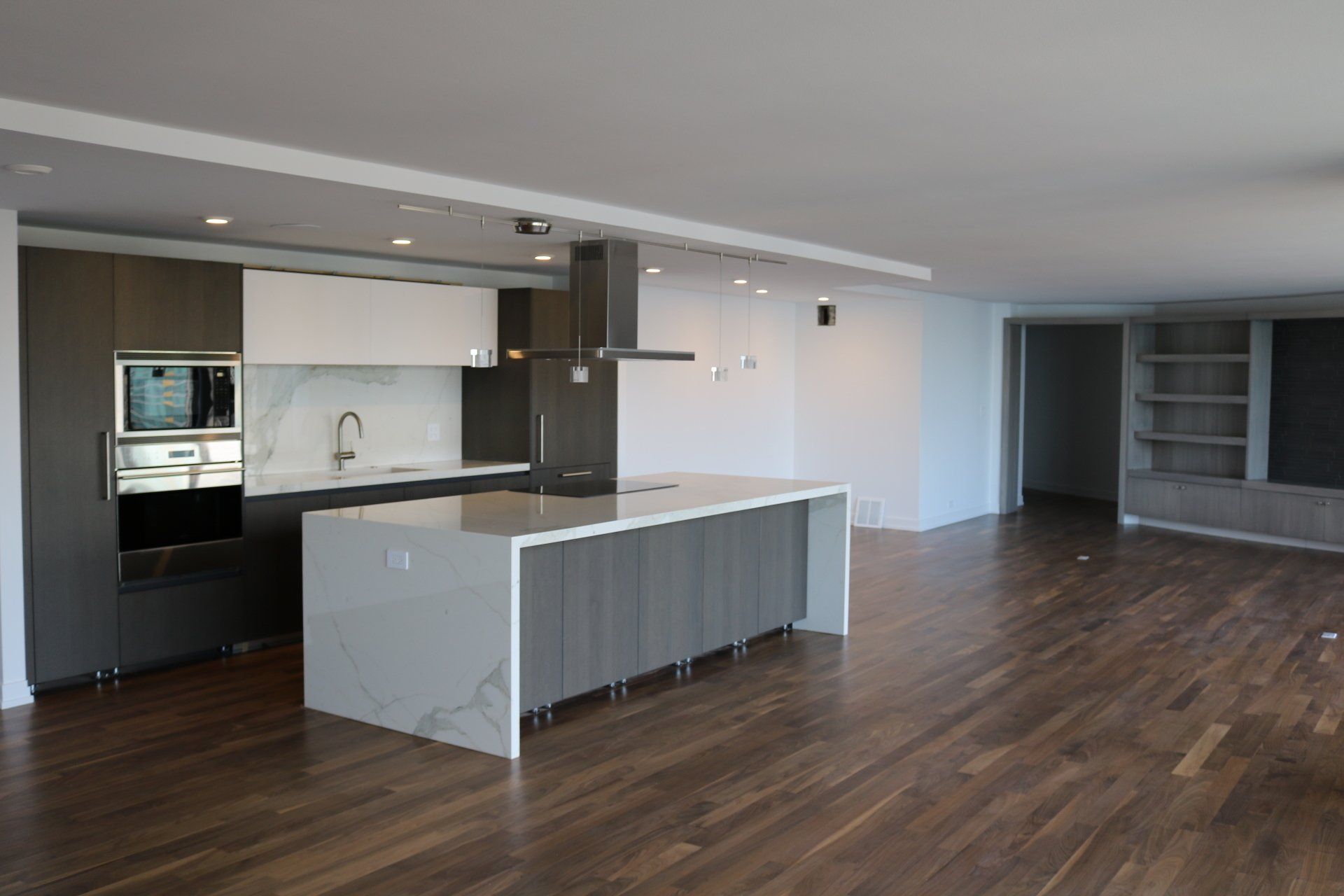 Modern kitchen with a large island, wood floors, and built-in cabinetry.