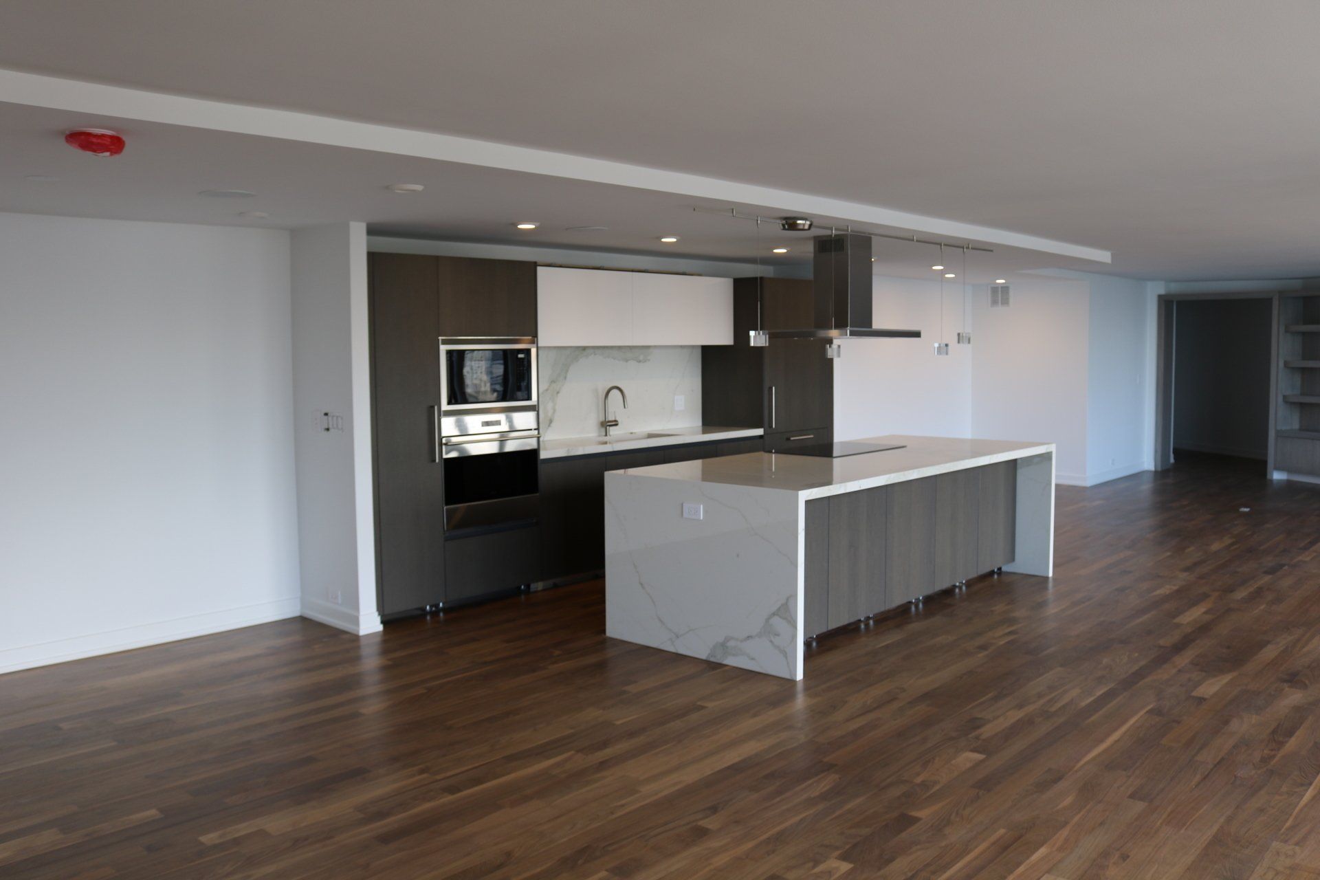 Modern kitchen with island, stainless steel appliances, and dark wood floors.