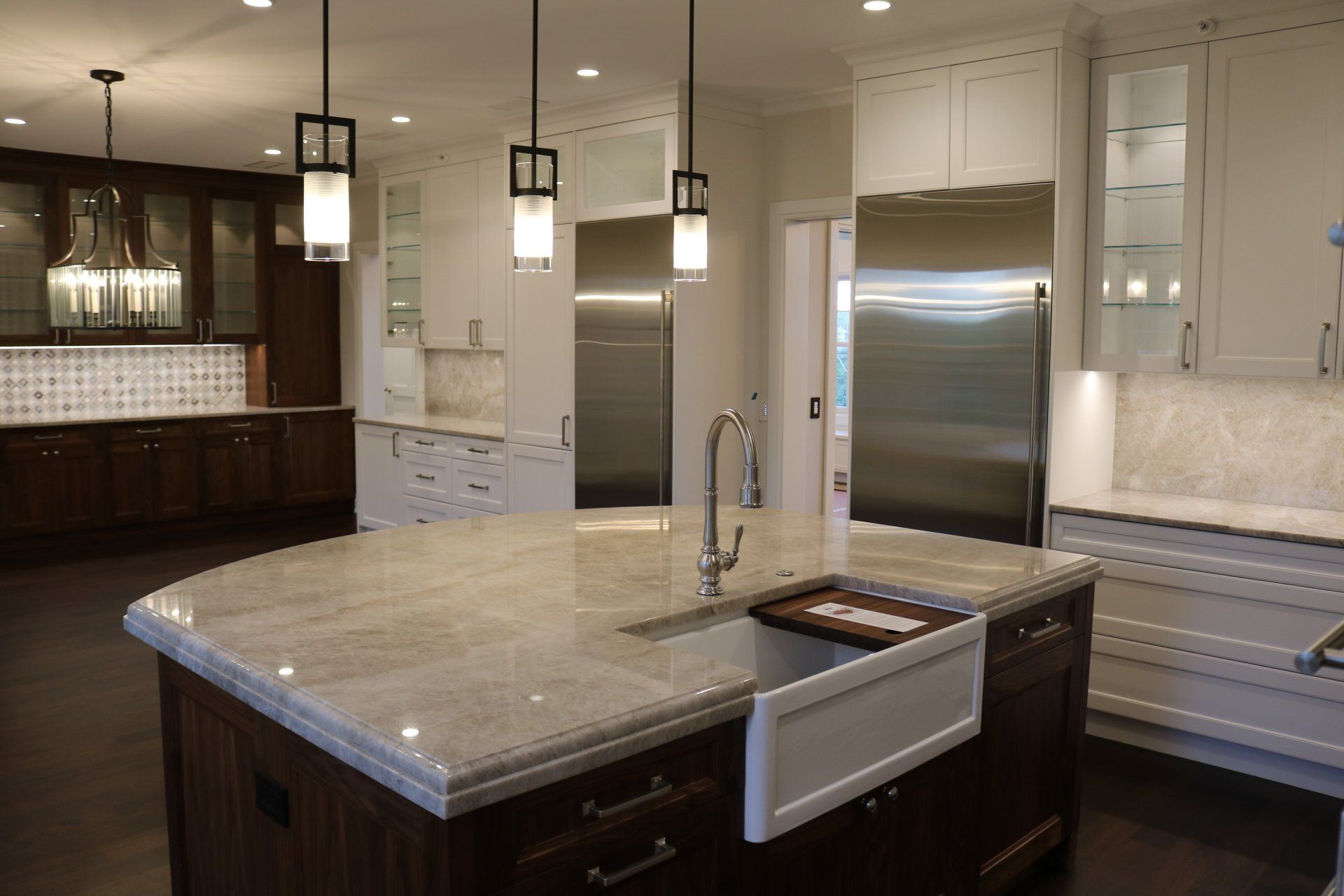 Modern kitchen with large island, stainless steel appliances, and white cabinetry.