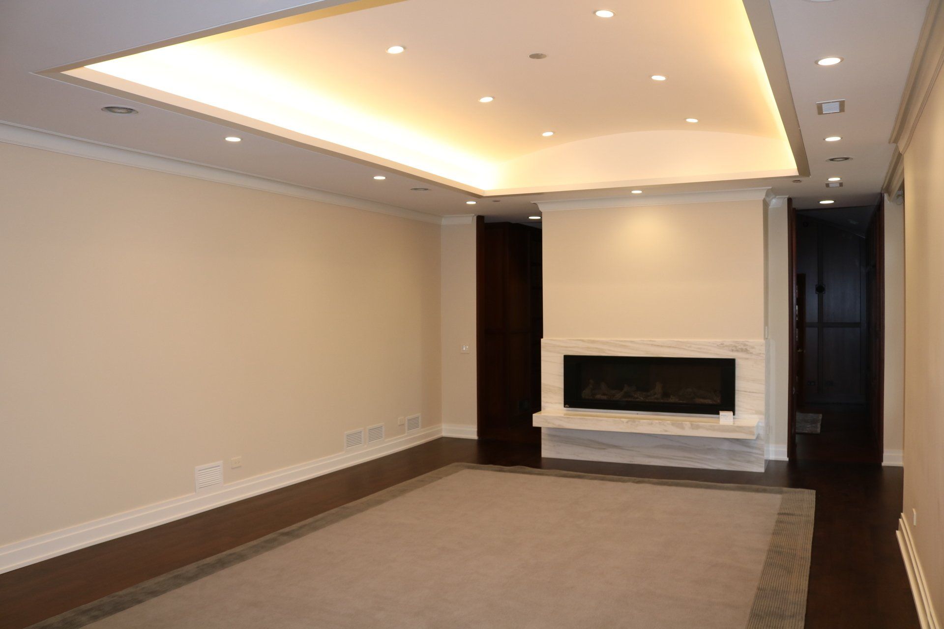 Empty modern living room with a fireplace and recessed lighting.
