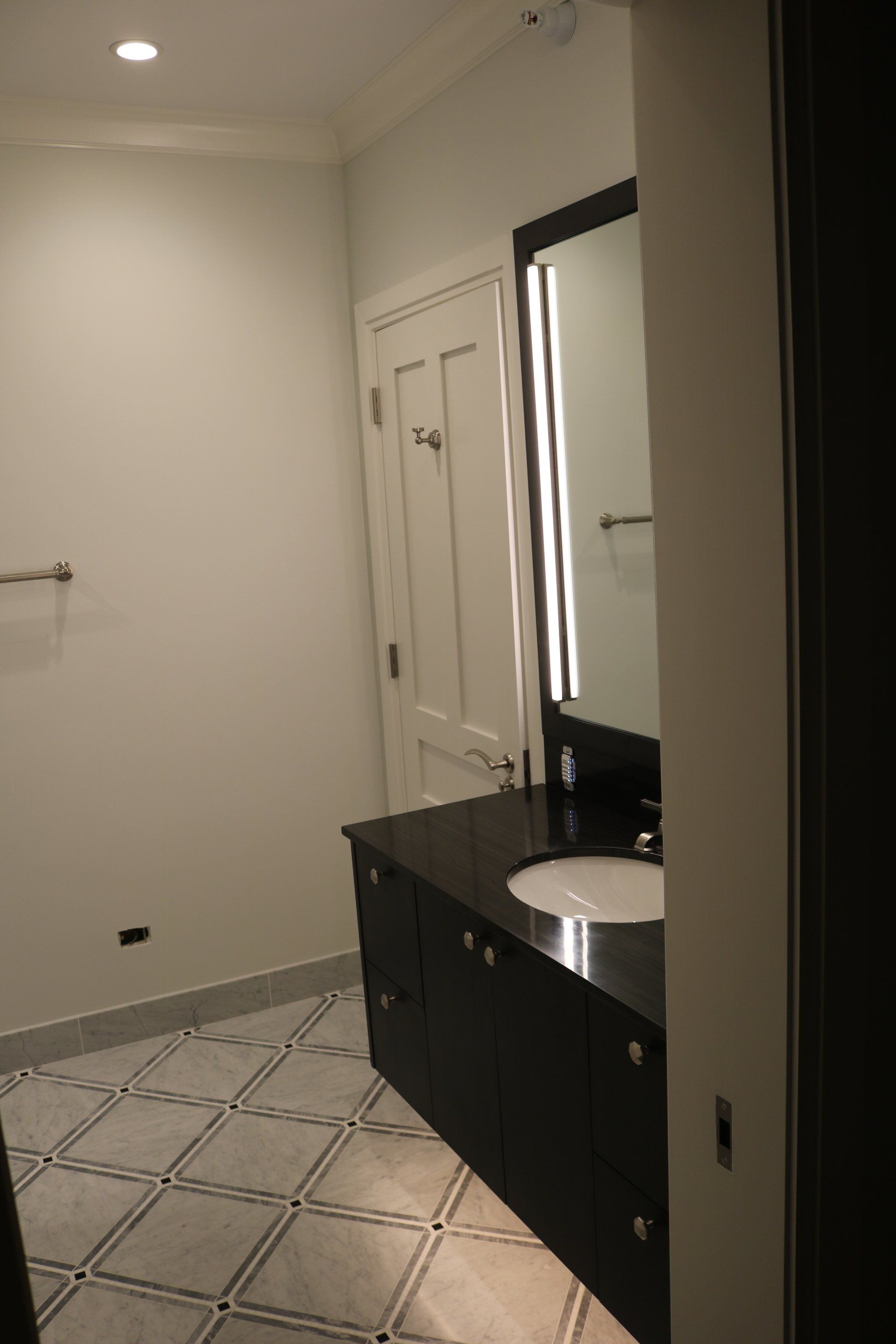Bathroom with black vanity, white sink, and patterned floor.