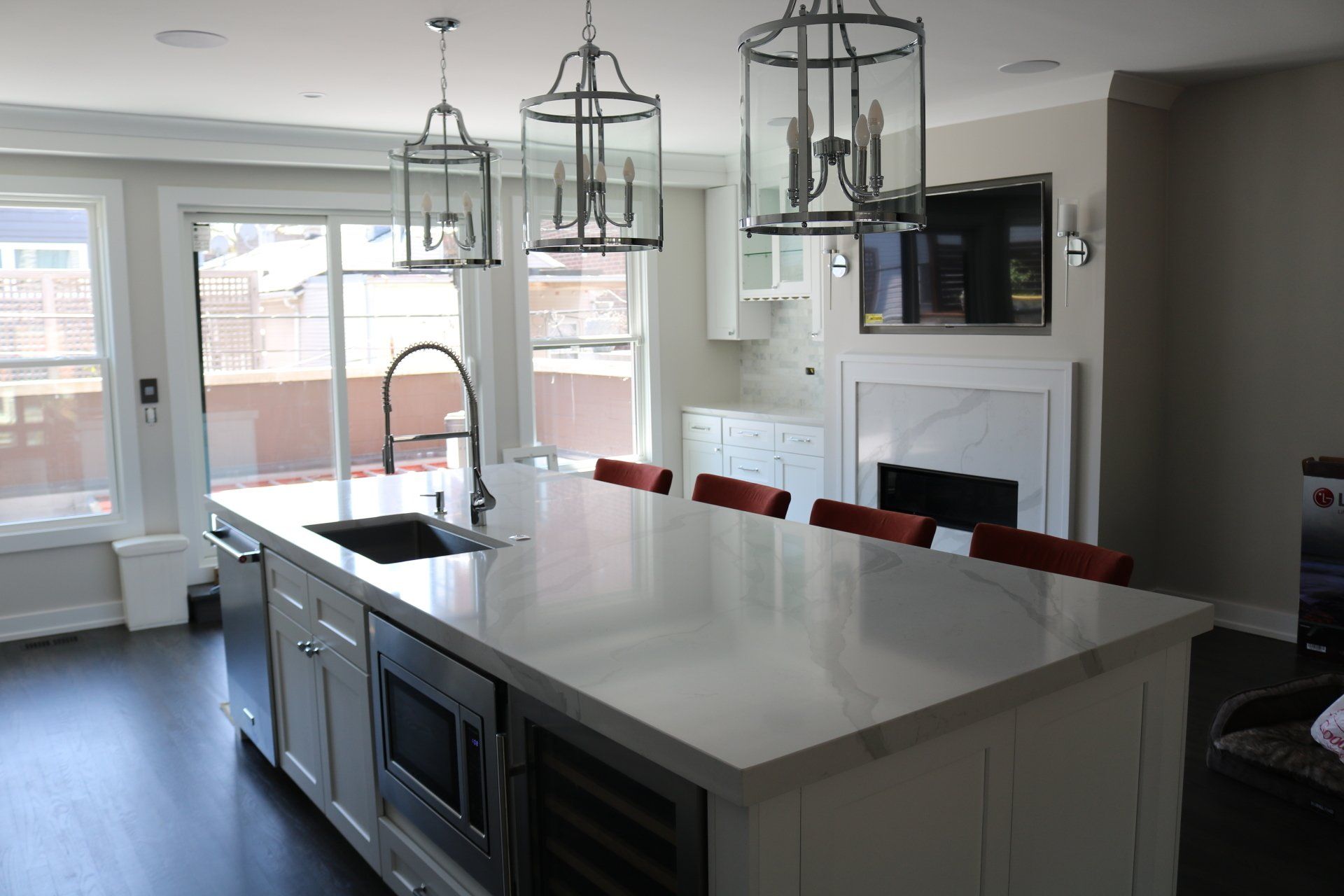 Modern kitchen with white island, dark cabinets, and gray walls. Island has sink, microwave, and wine cooler.