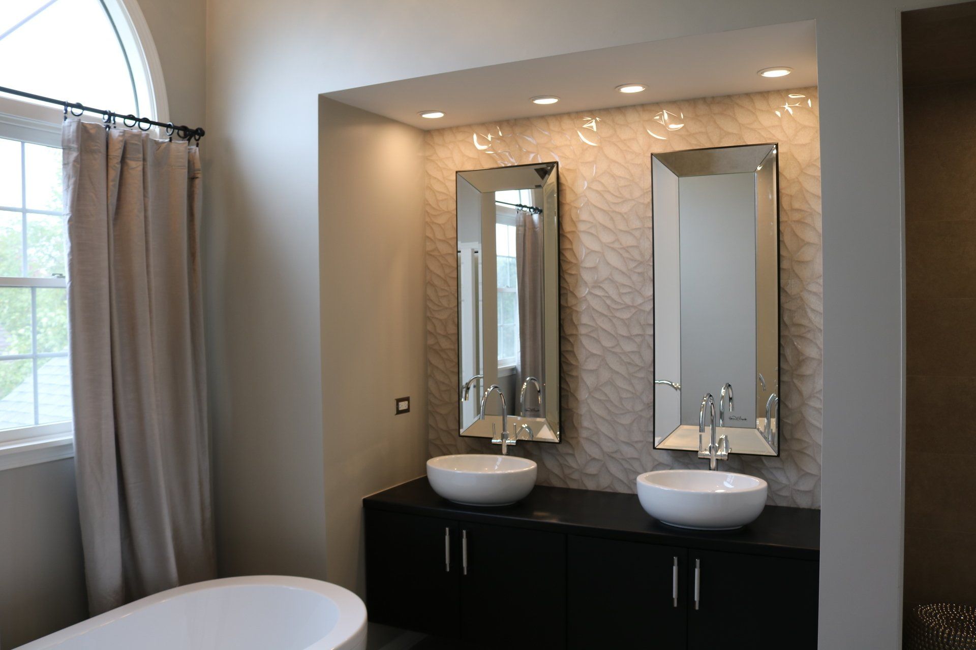 Bathroom with two vessel sinks, mirrors, and a tub. Neutral tones.