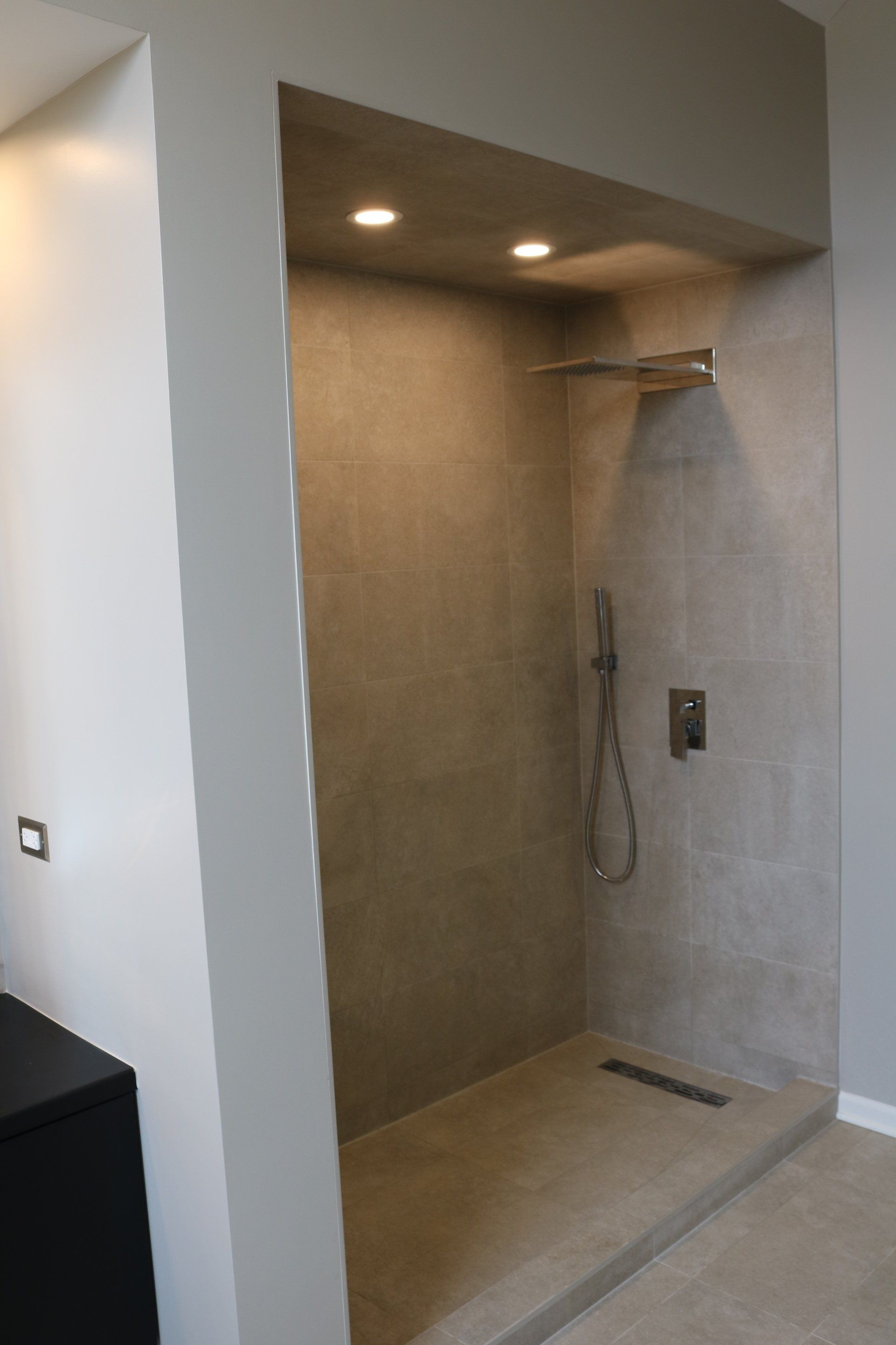 Walk-in shower with gray tiled walls, built-in bench, and recessed lighting.
