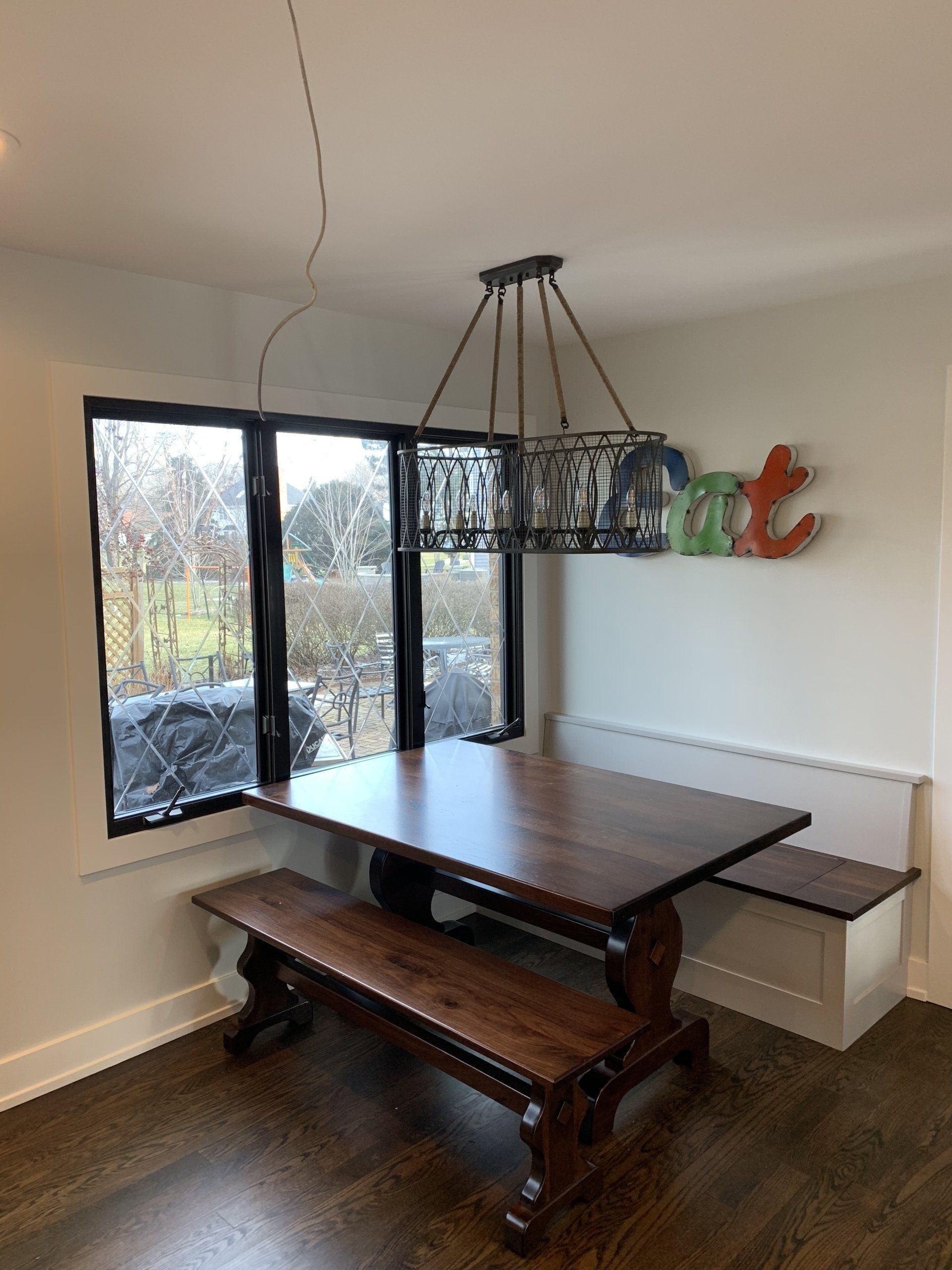 Dining area: dark wooden table with bench, window, built-in white bench, chandelier, 