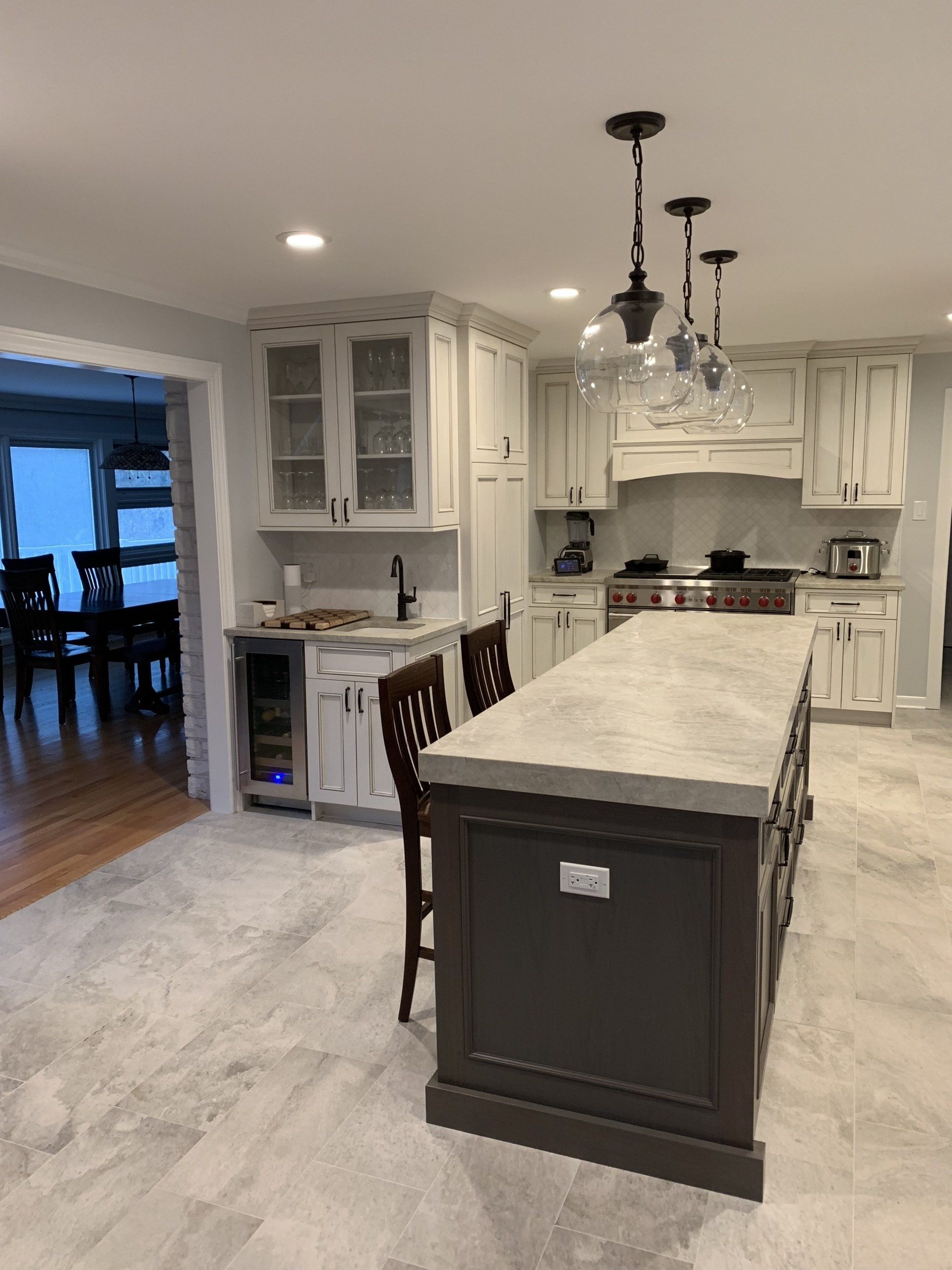 Modern kitchen with island and cabinets. Gray countertops, dark brown island base. White and light-gray cabinetry.