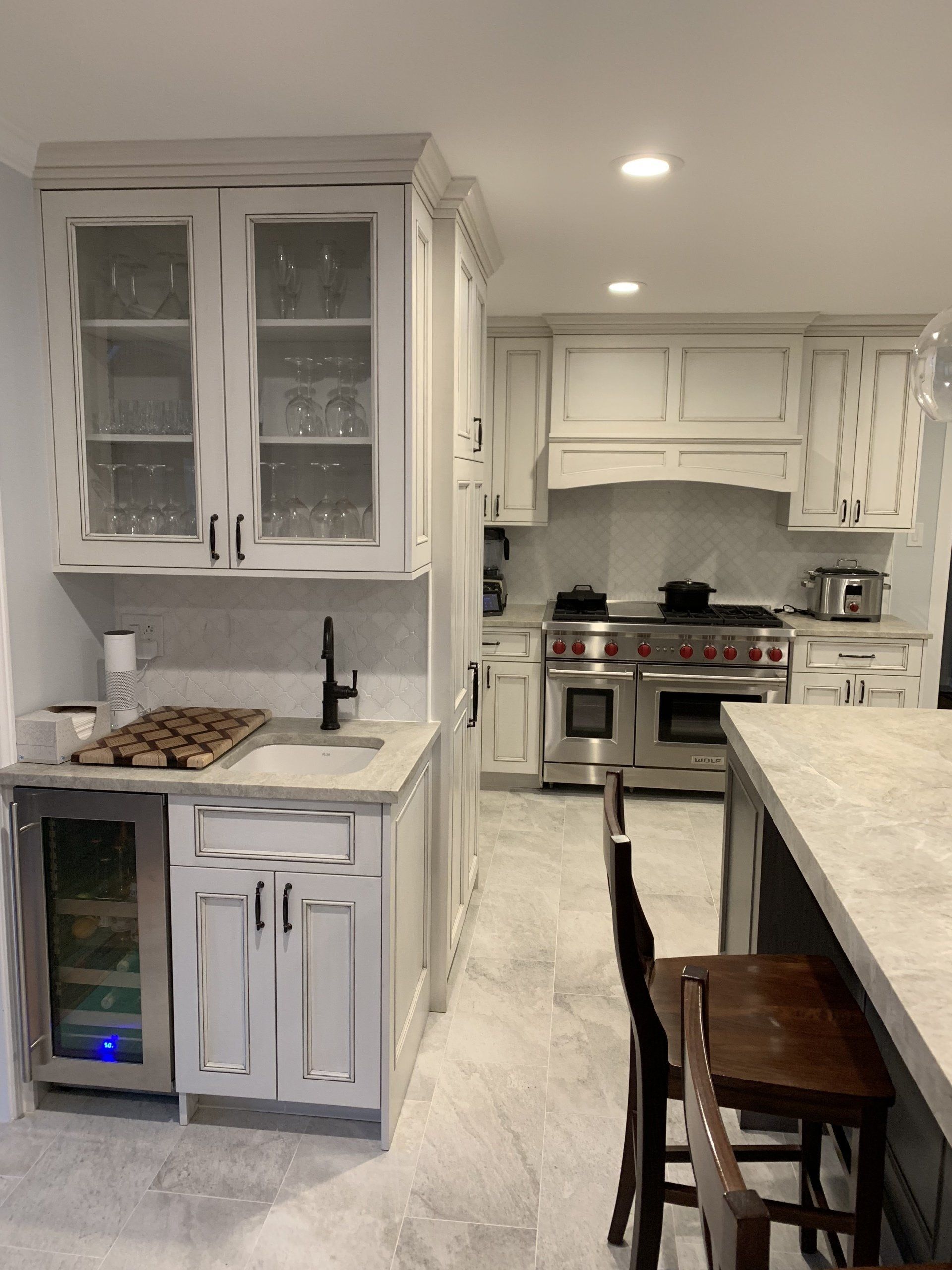 A kitchen with white cabinets, a wine fridge, and a stainless steel range.