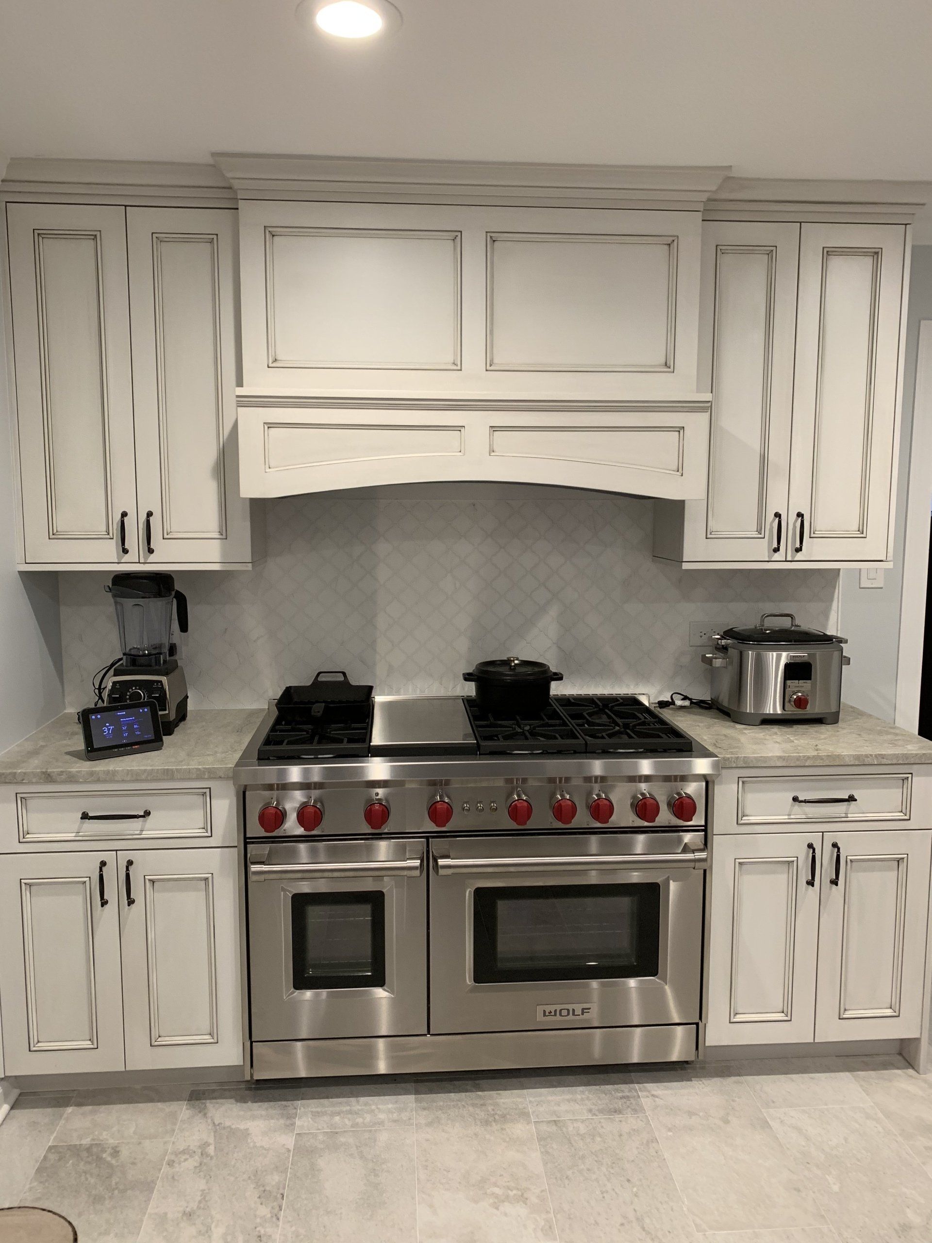 Kitchen with white distressed cabinets, stainless steel range, and light countertops.