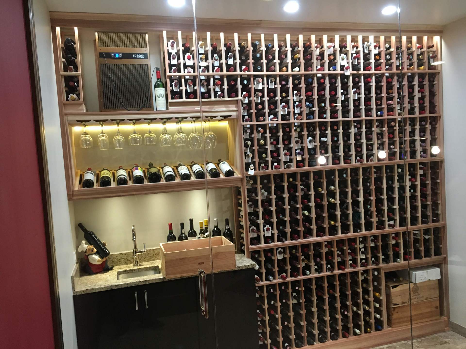 Wine cellar with racks full of bottles, a bar area, and a cooler. Wooden and lit.