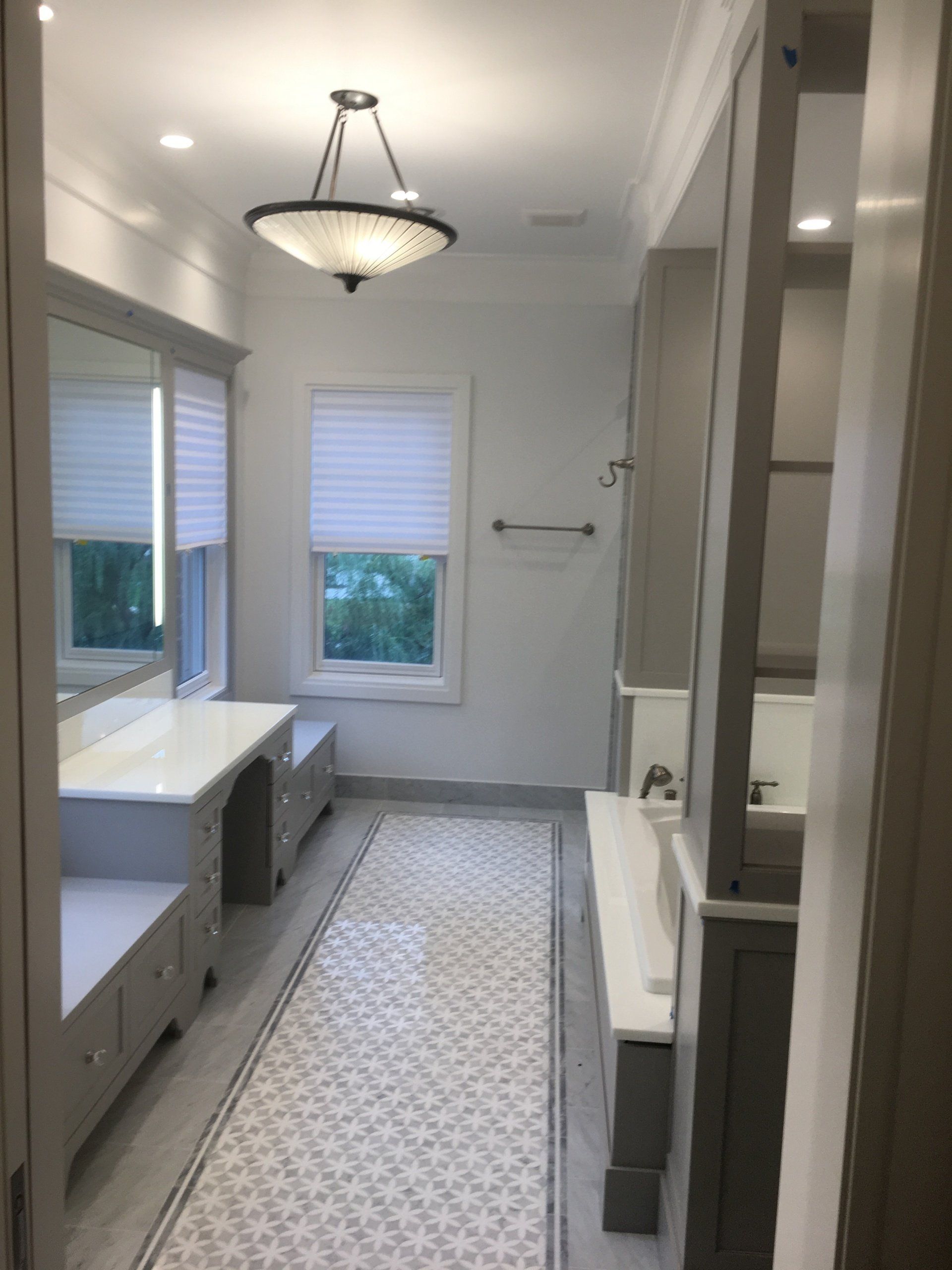 Bathroom with vanity, window, and patterned floor. Light grey and white color scheme.