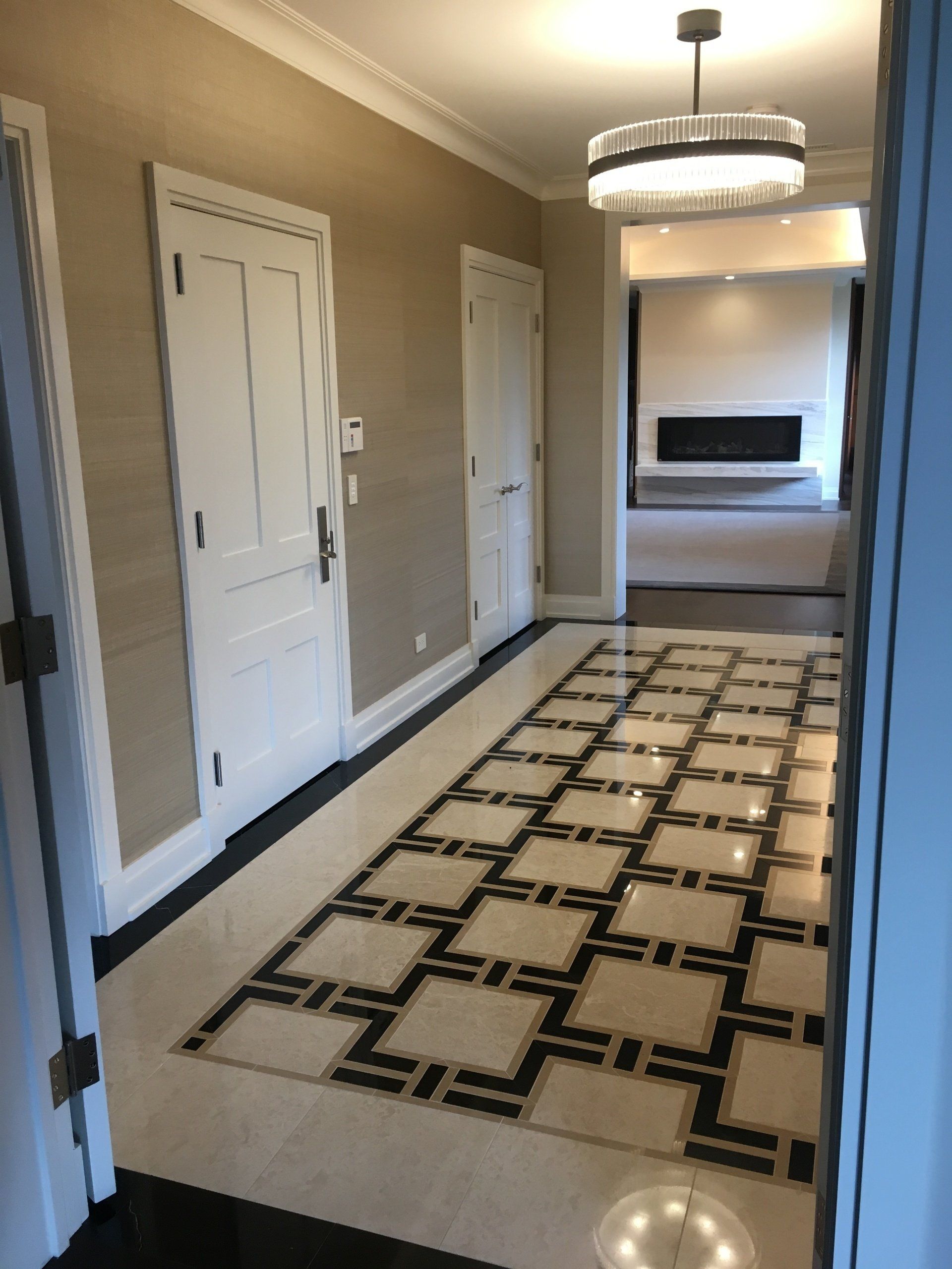 Hallway with patterned floor, white doors, and a fireplace at the end.