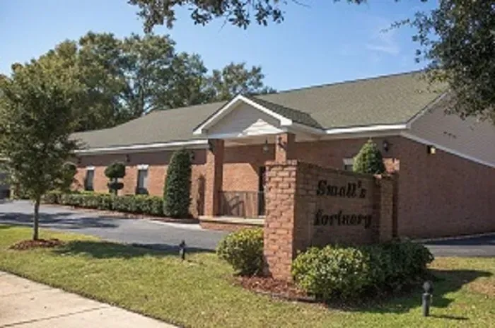 A brick building with a green roof and a brick sign in front reading 