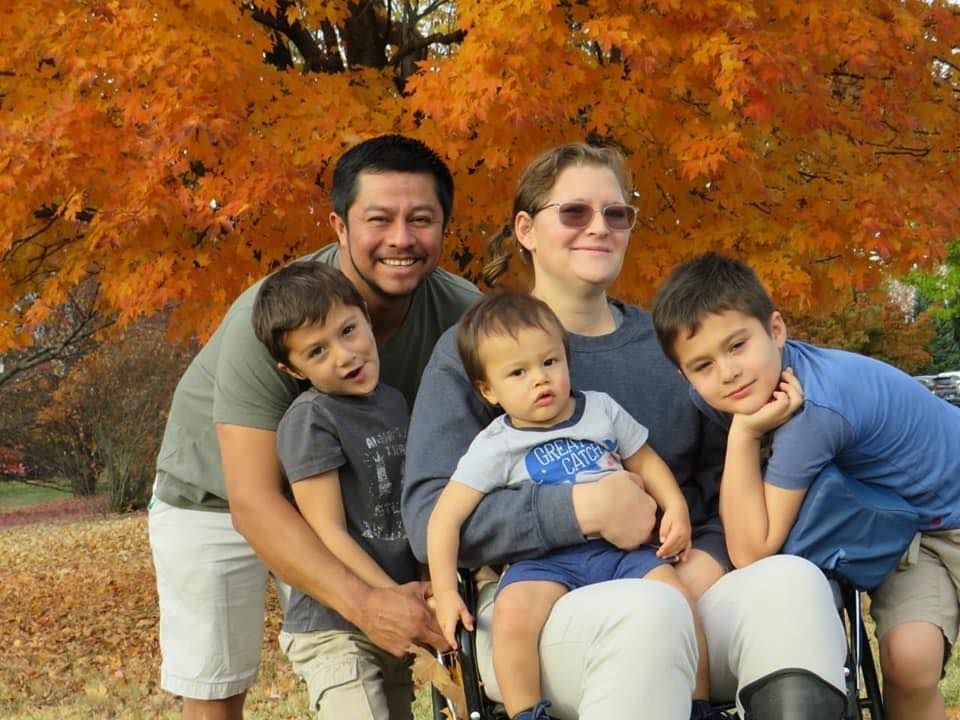 A family is posing for a picture in front of a tree.