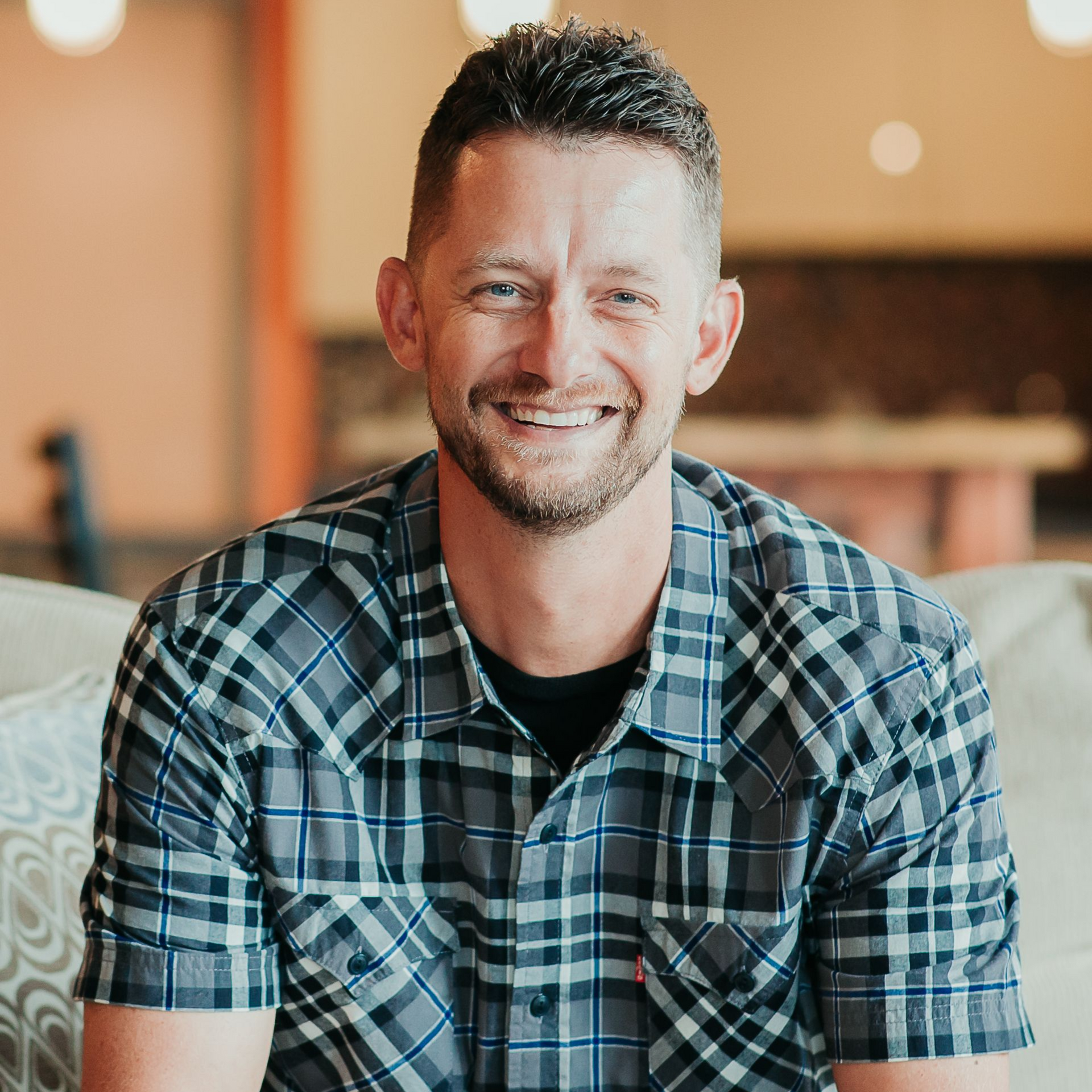 A man with a beard is smiling for the camera while wearing a blue shirt.