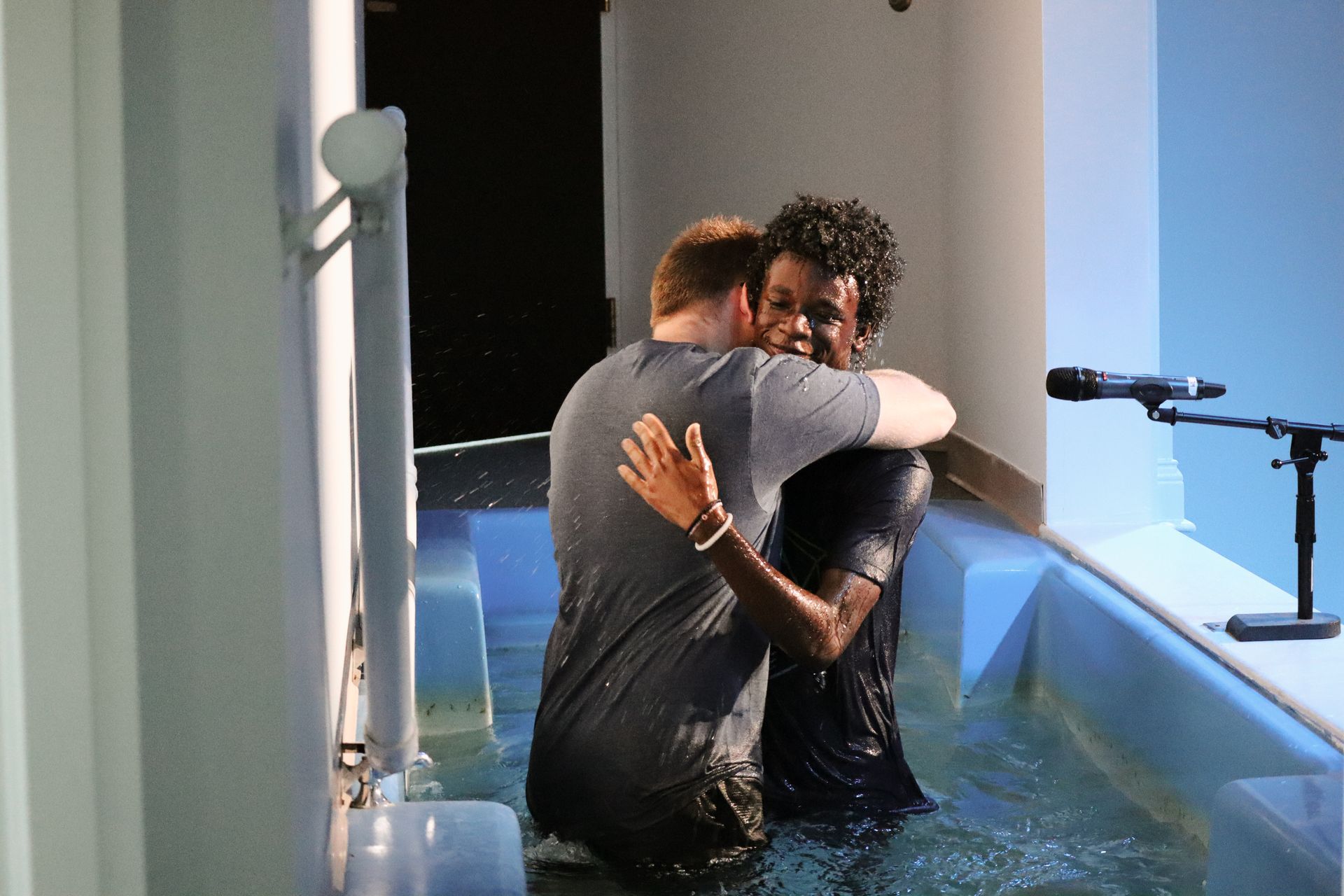 Two men are hugging each other in a pool of water.