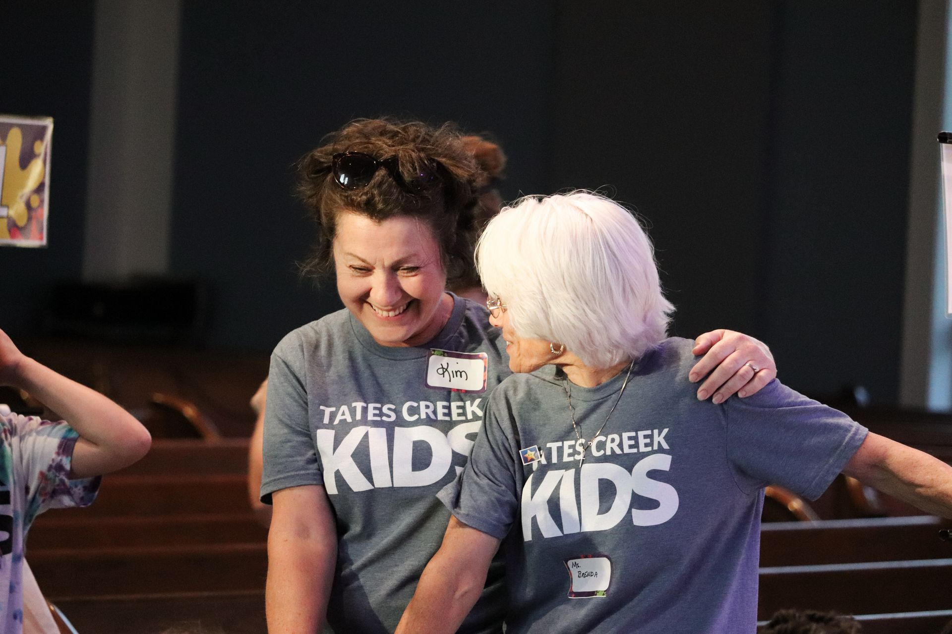 Two women wearing tates creek kids shirts are hugging each other