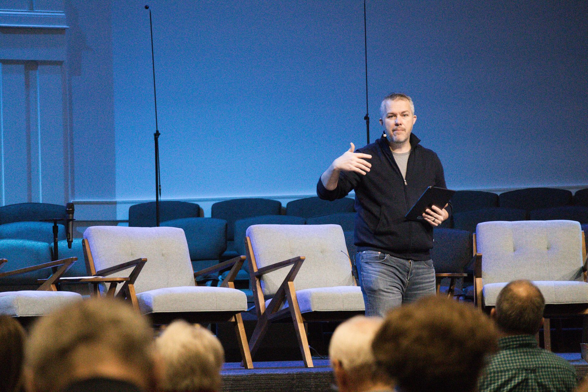 A man is standing on a stage giving a speech to a group of people.