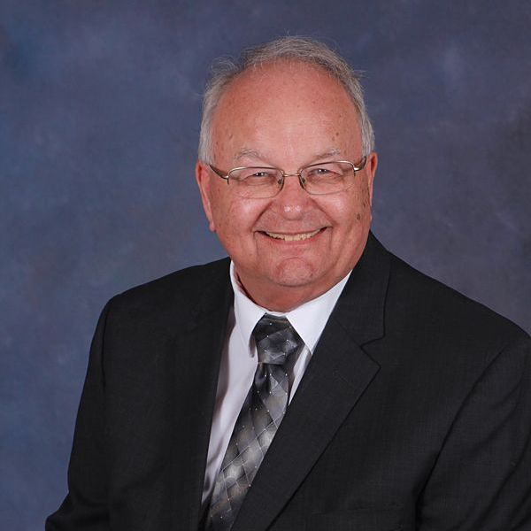 A man wearing glasses and a plaid shirt is smiling for the camera.