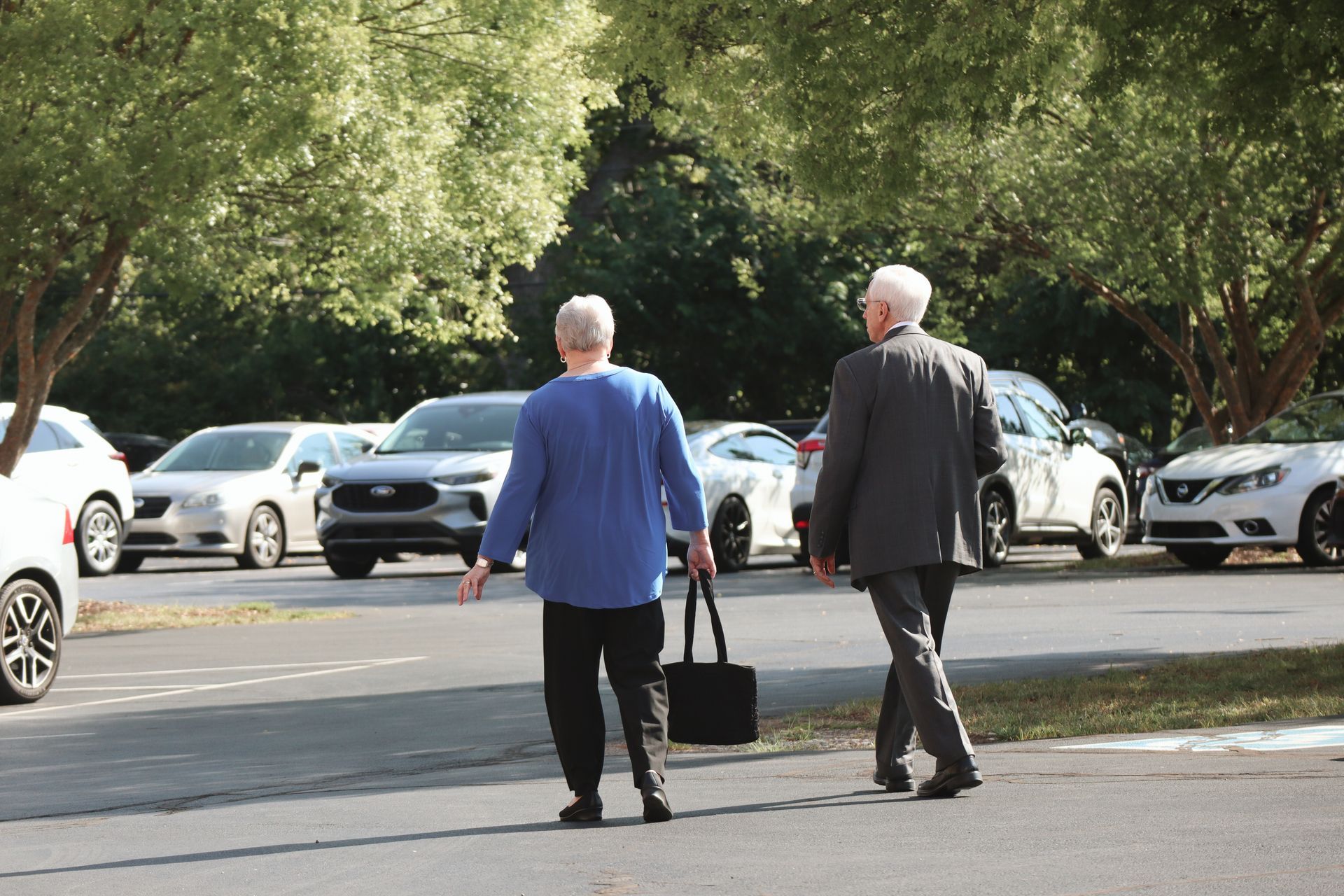 A man and a woman are walking in a parking lot.