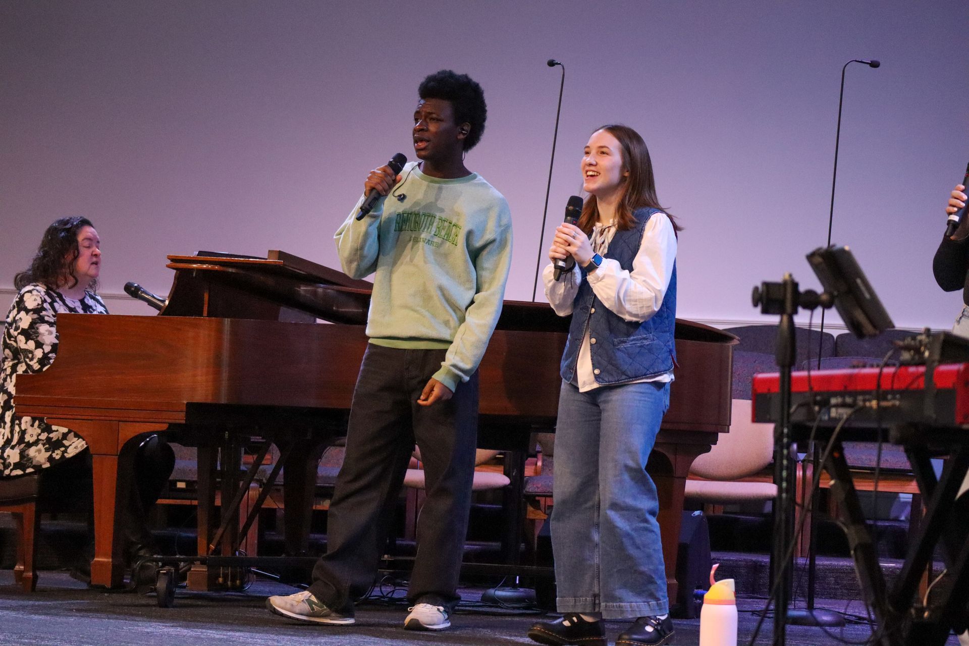 A man and a woman are singing into microphones on a stage.
