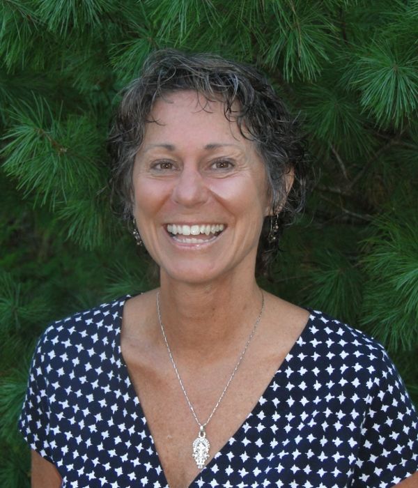 A woman in a blue and white polka dot shirt is smiling