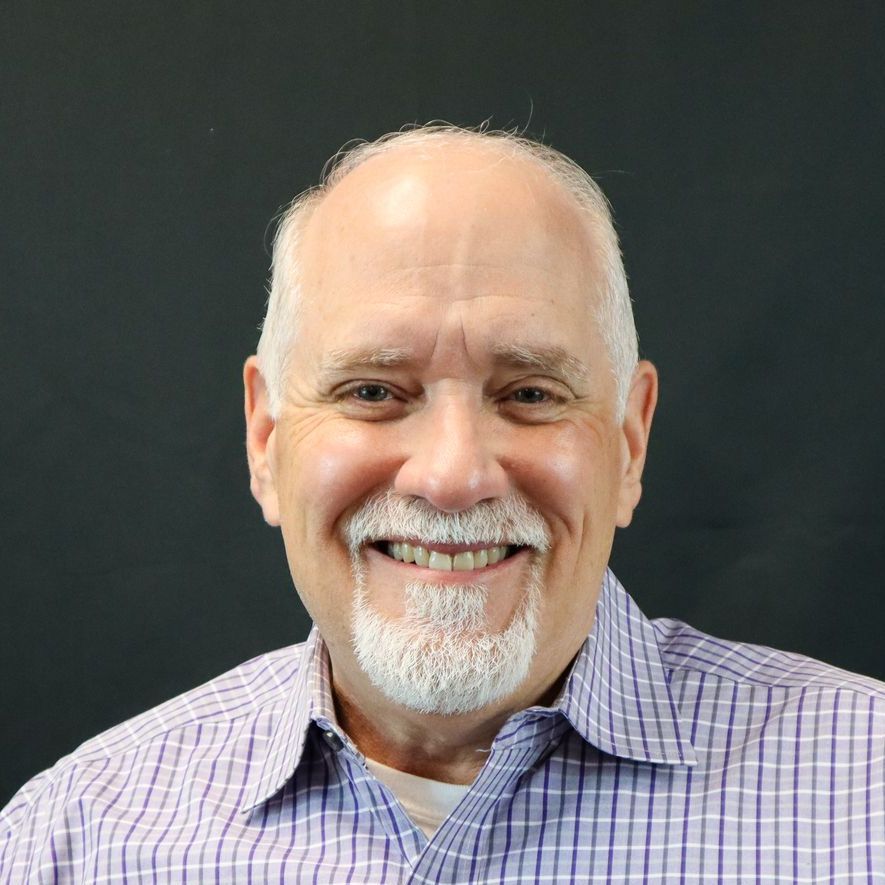 A man with a beard and a plaid shirt is smiling for the camera.