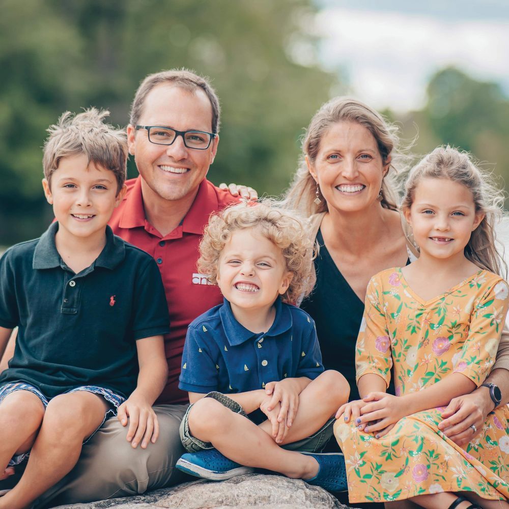 A family is posing for a picture while sitting on a rock.